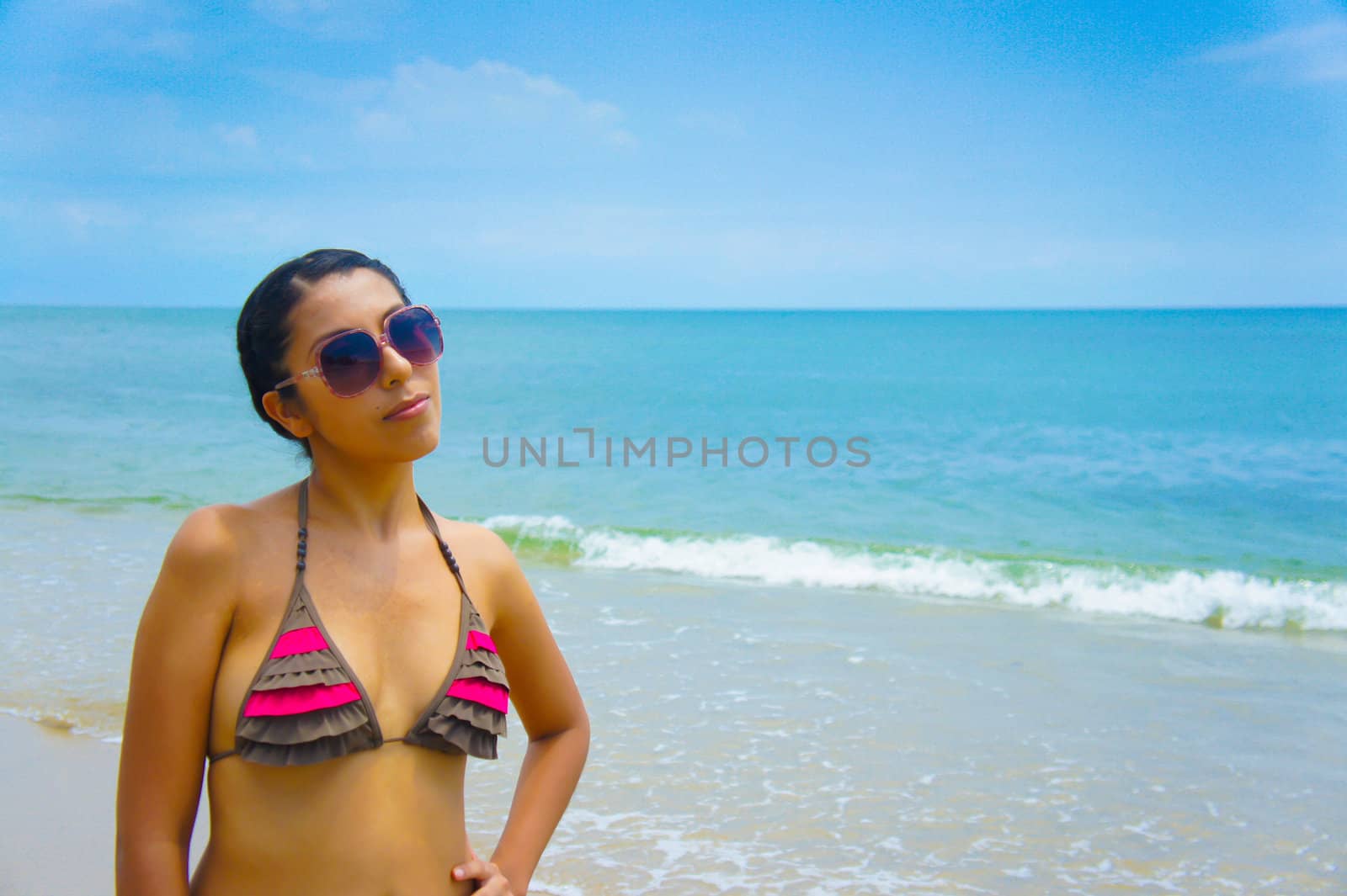 A girl standing on a tropical beach with ocean in the background. 