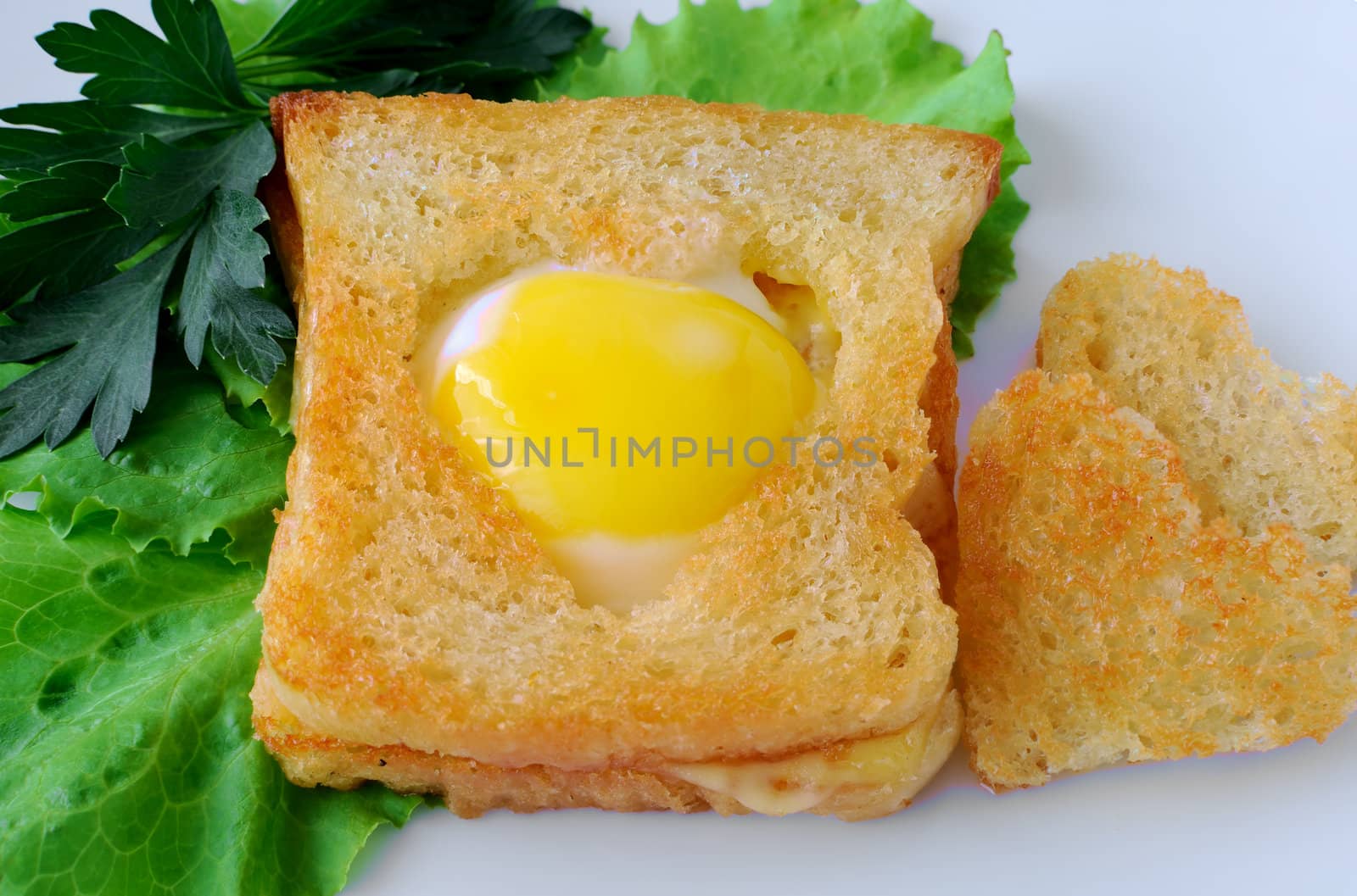 Toast with egg in the form of a heart on a platter with lettuce leaves