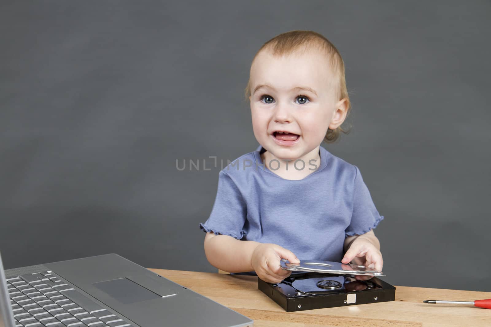 child working at open hard drive in grey background with laptop computer