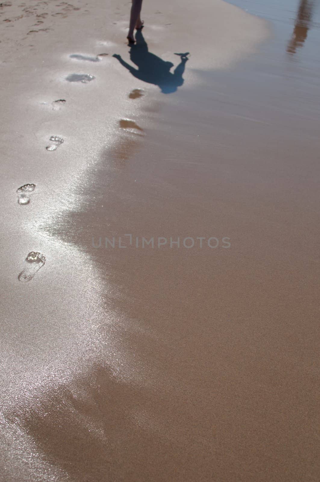 Woman walking barefoot on sunny beach in summer day