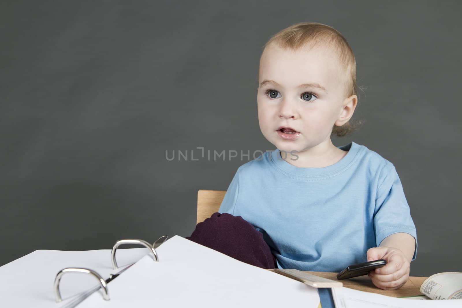 young child at small desk in grey background