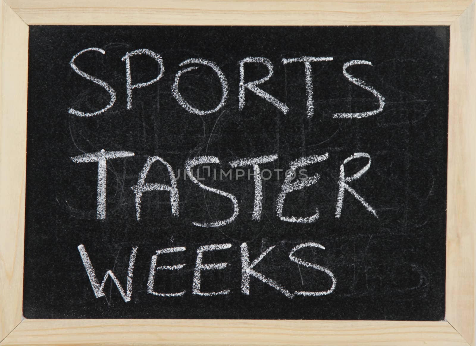 A blackboard with a wooden border with the words 'SPORTS TASTER WEEKS' written by hand in white chalk.