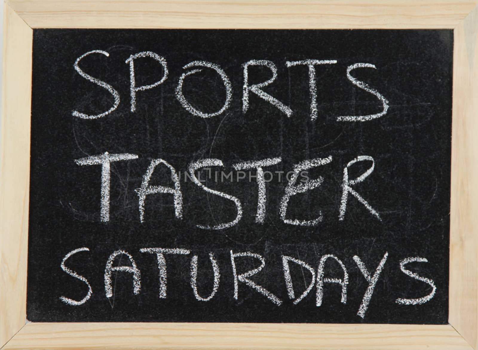 A blackboard with a wooden border with the words 'SPORTS TASTER SATURDAYS' written by hand in white chalk.
