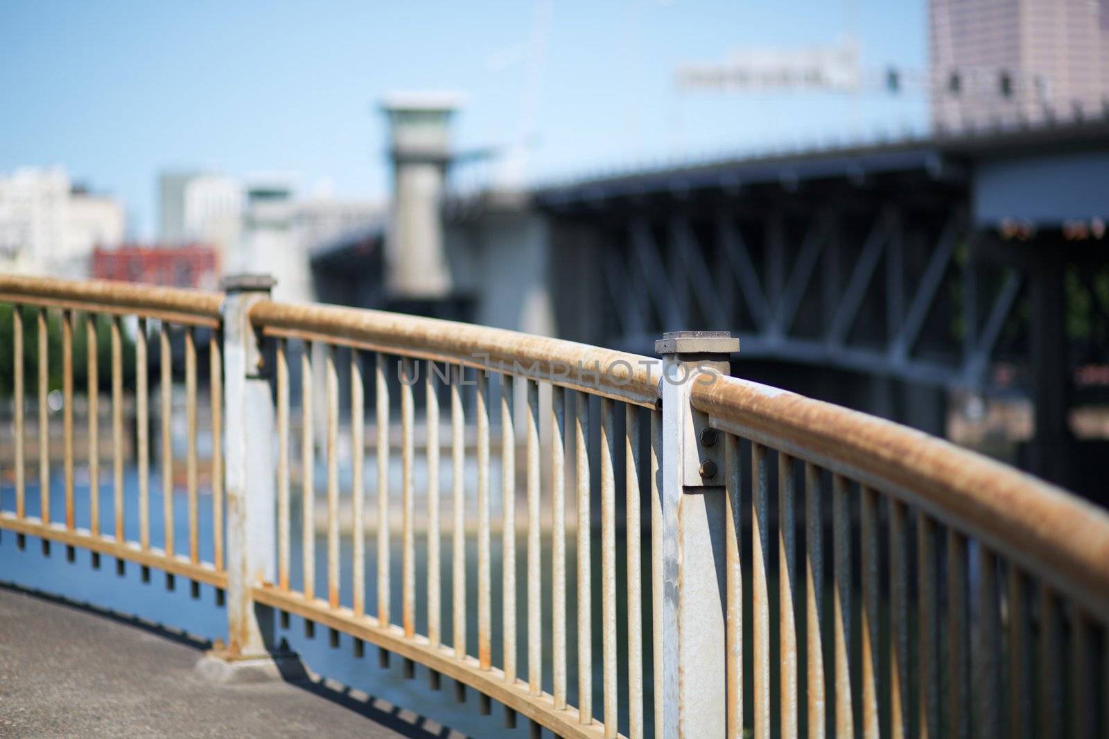 Curved steel railing with soft focus bridge and sky in Portland Oregon