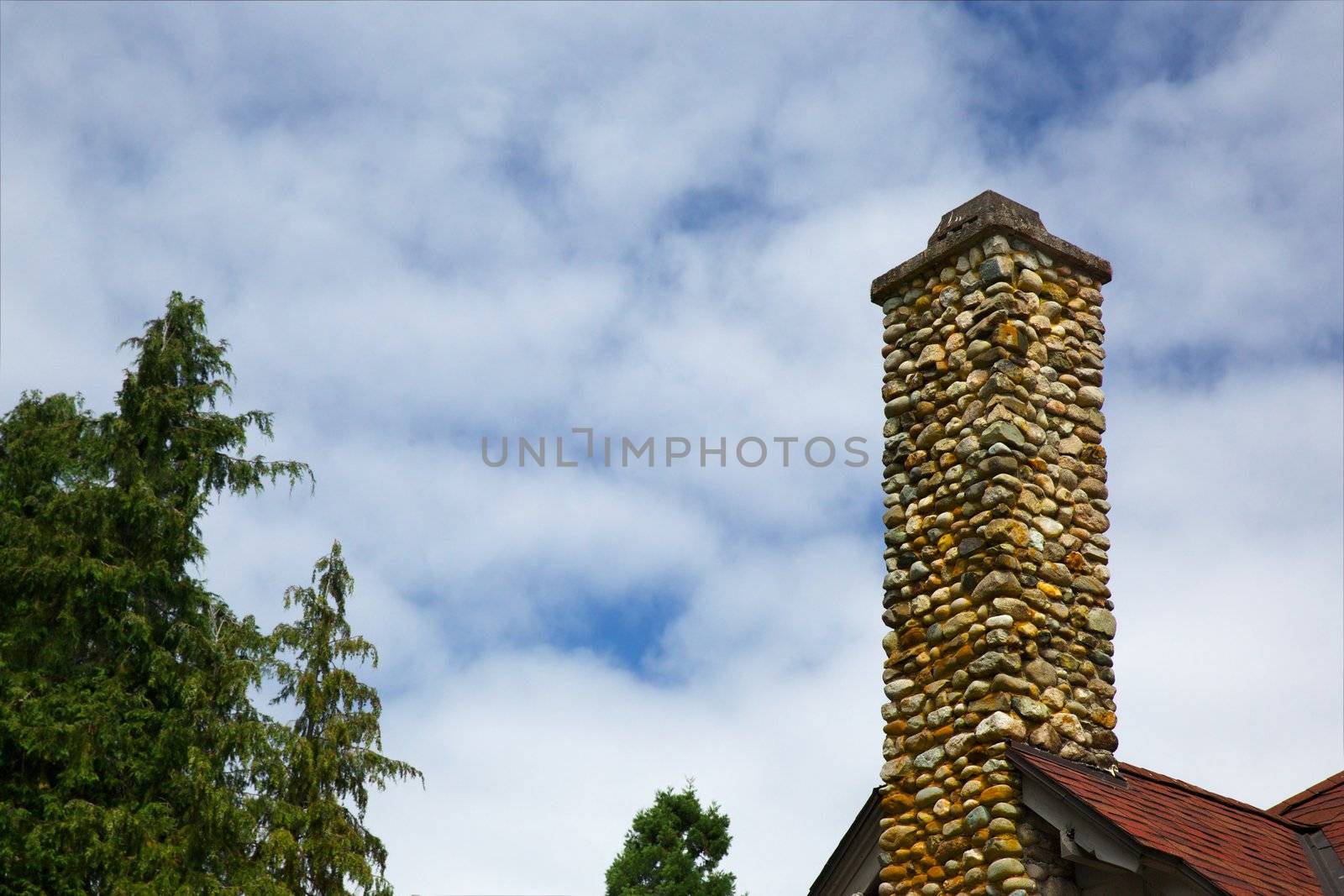 Multi-color stone chimney against a puffy clouded sky