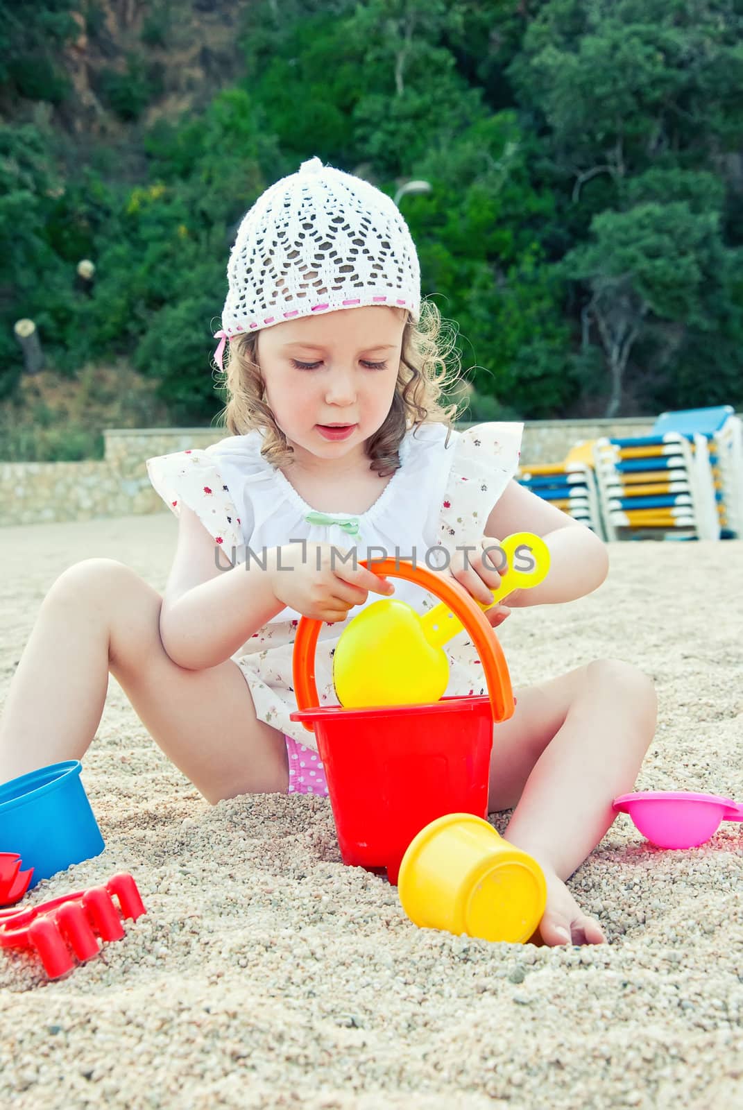 Little girl playing with toys on the beach by dmitrimaruta