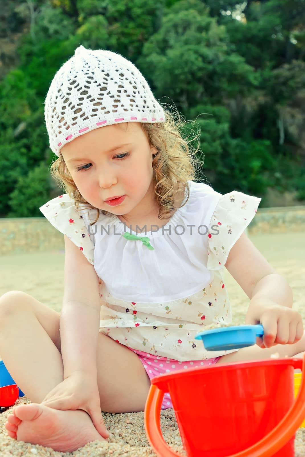 Little girl playing with toys on the beach by dmitrimaruta