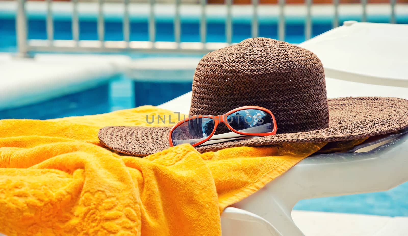 Straw hat with towel near the swimming pool by dmitrimaruta