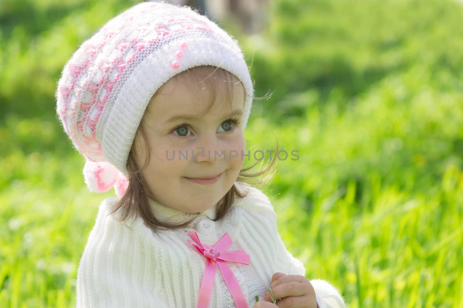 Smiling cute baby girl with hat over green grass