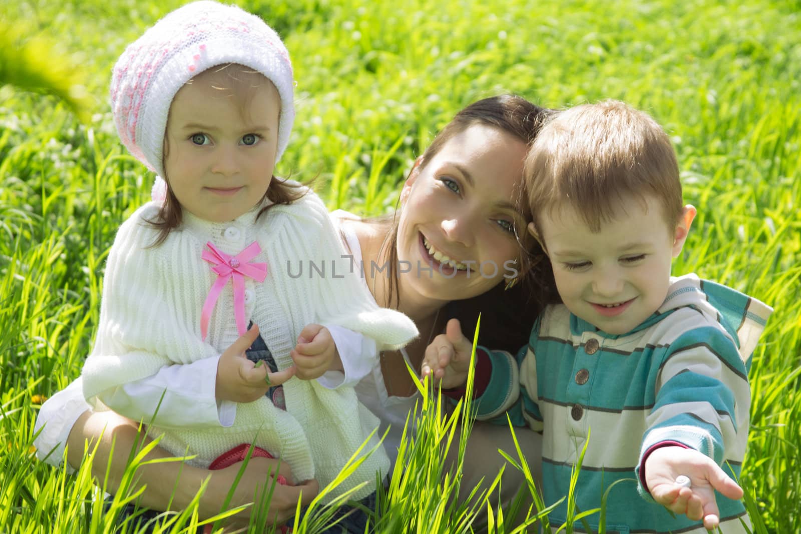 Happy mother with two children among green grass