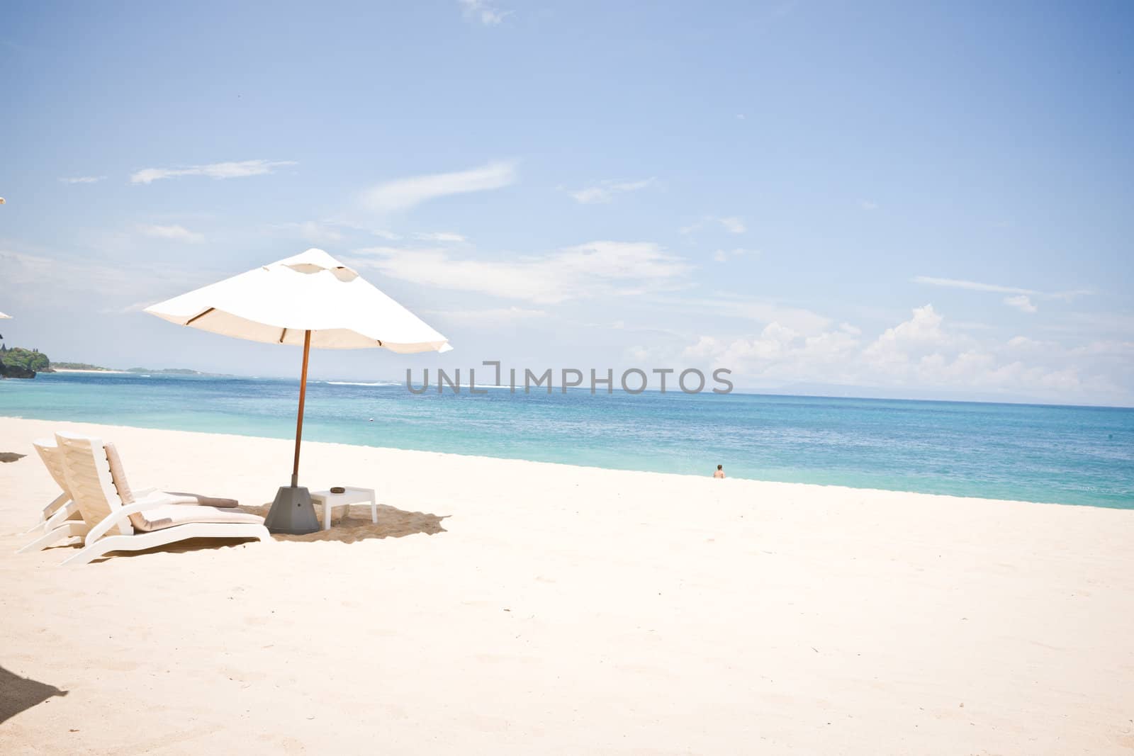 Tranquil beach and white sand with umbrella and lounge chairs
