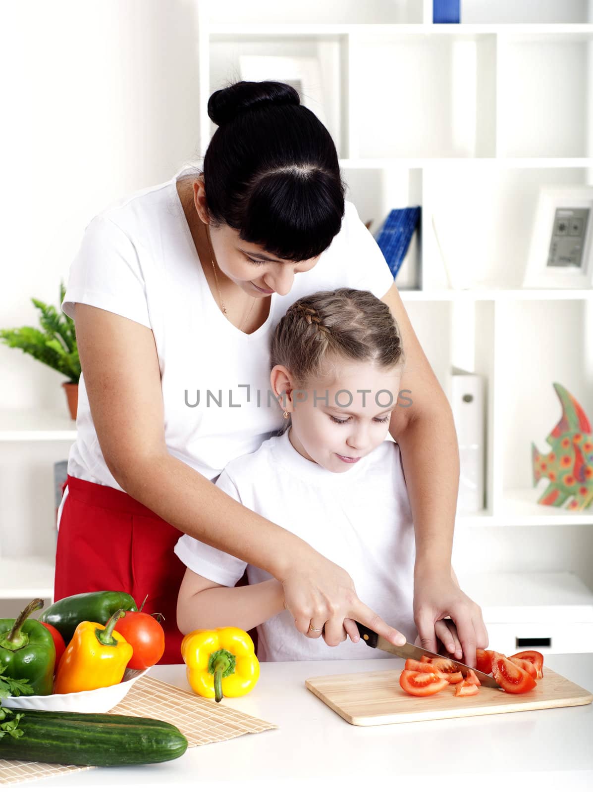 Mother and daughter cooking vegetable salad together