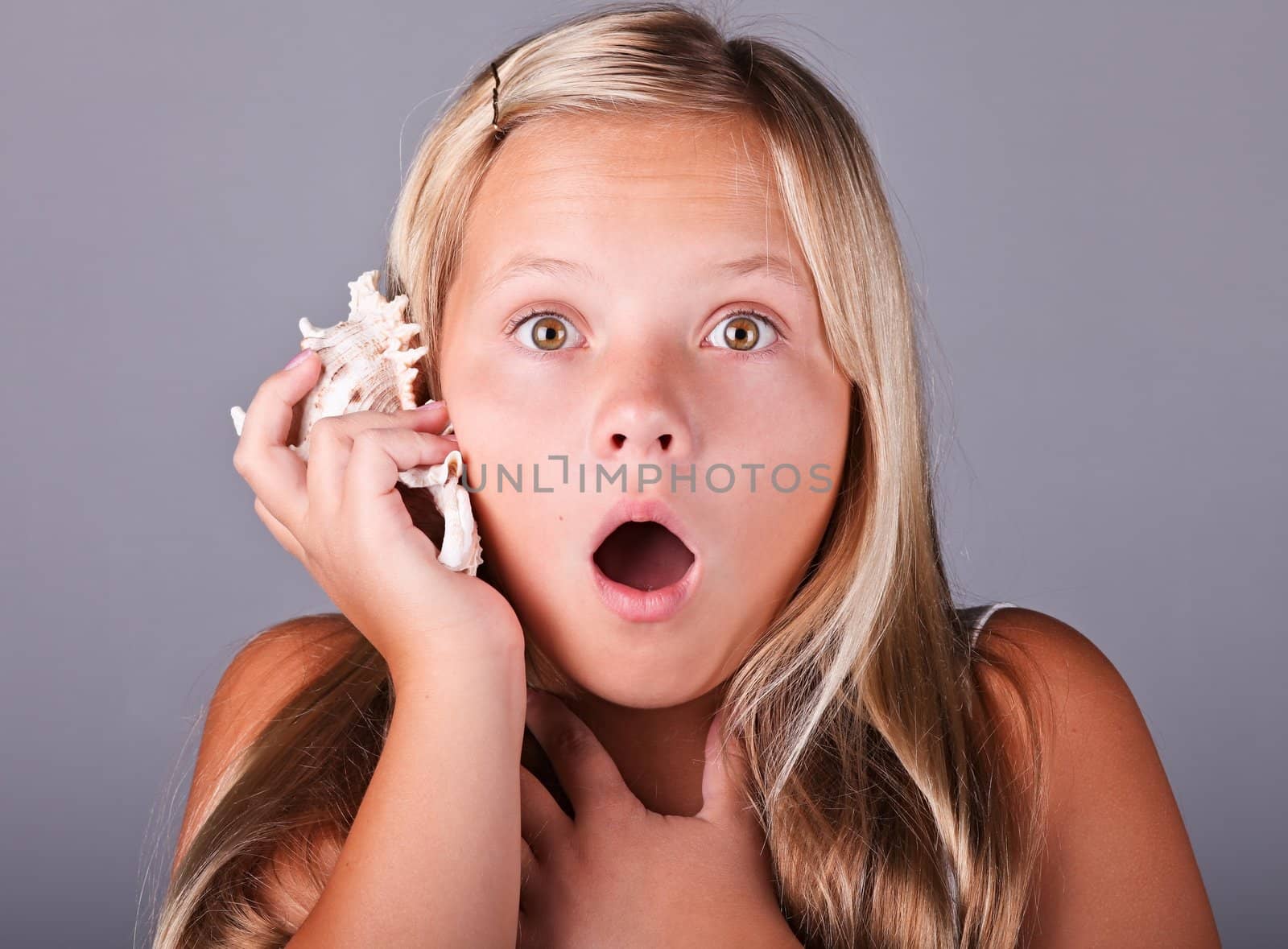 Young girl with shell listening to the sea