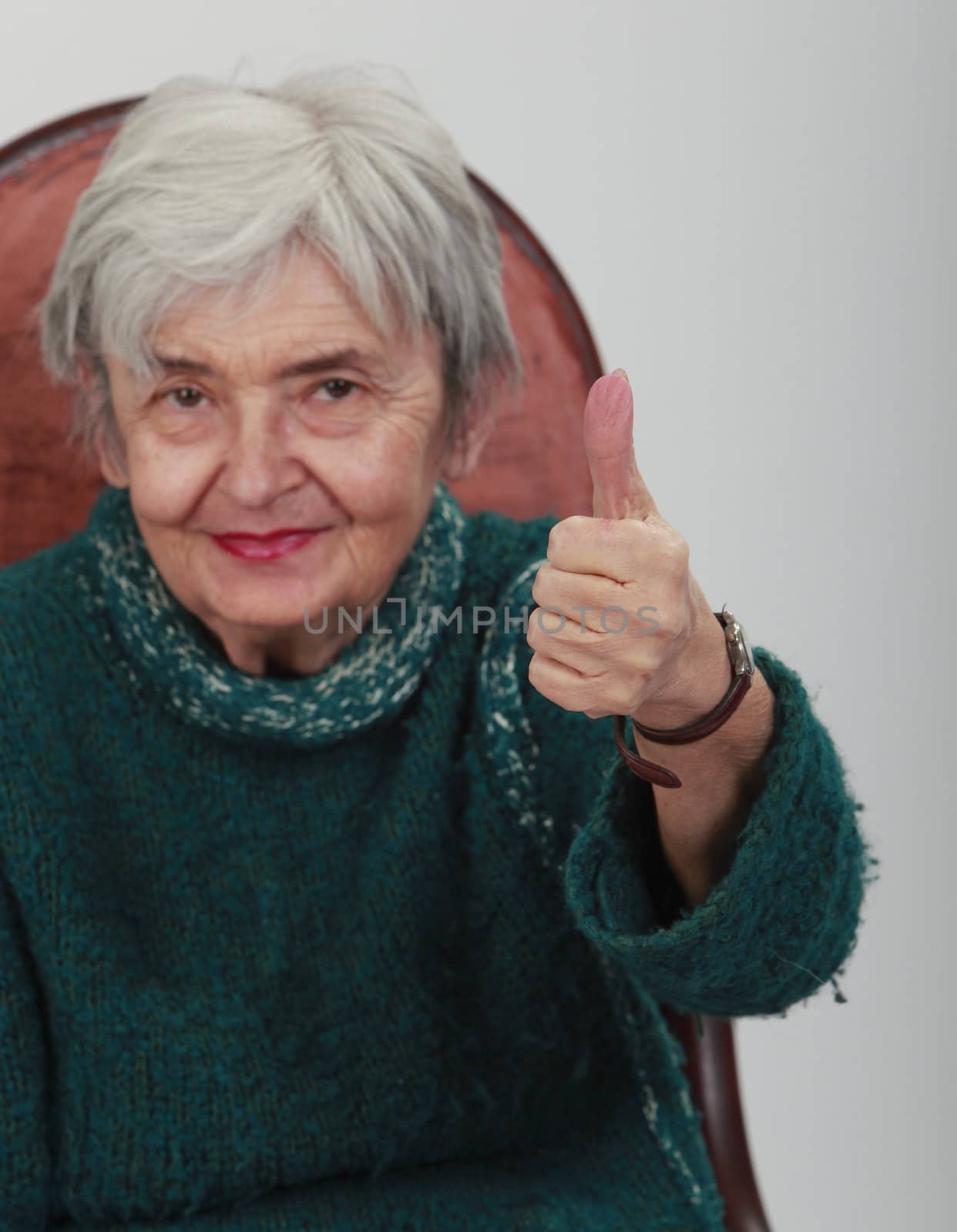 Image of a happy senior woman with thumb up.Selective focus on the hand.