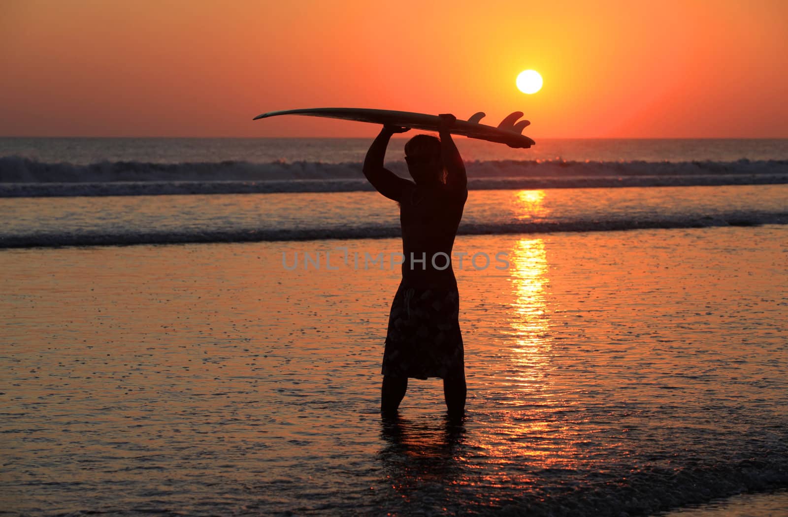 Silhouettes of surfer at red sunset. Kuta beach. Bali