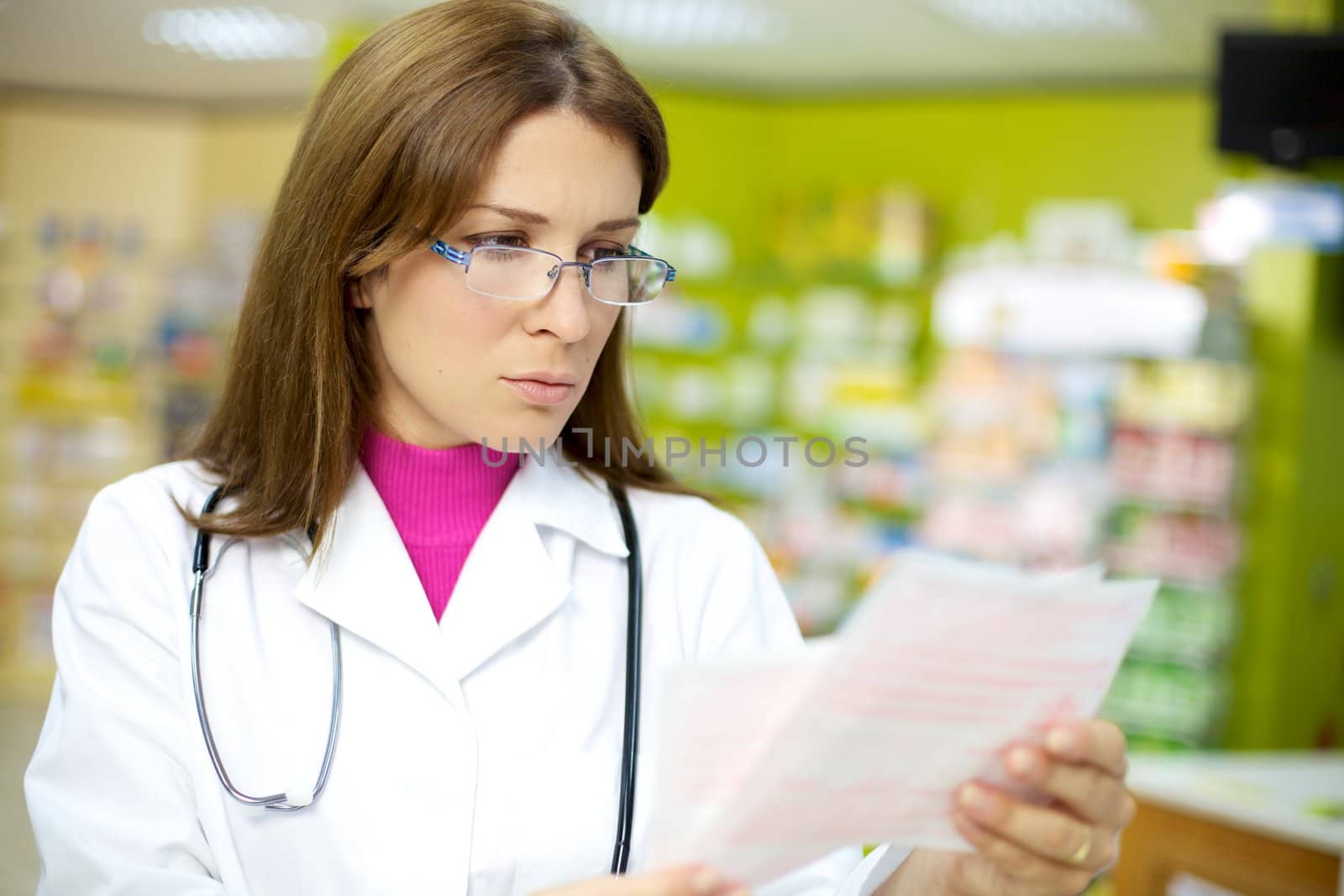 Female doctor reading prescription in pharmacy by fmarsicano