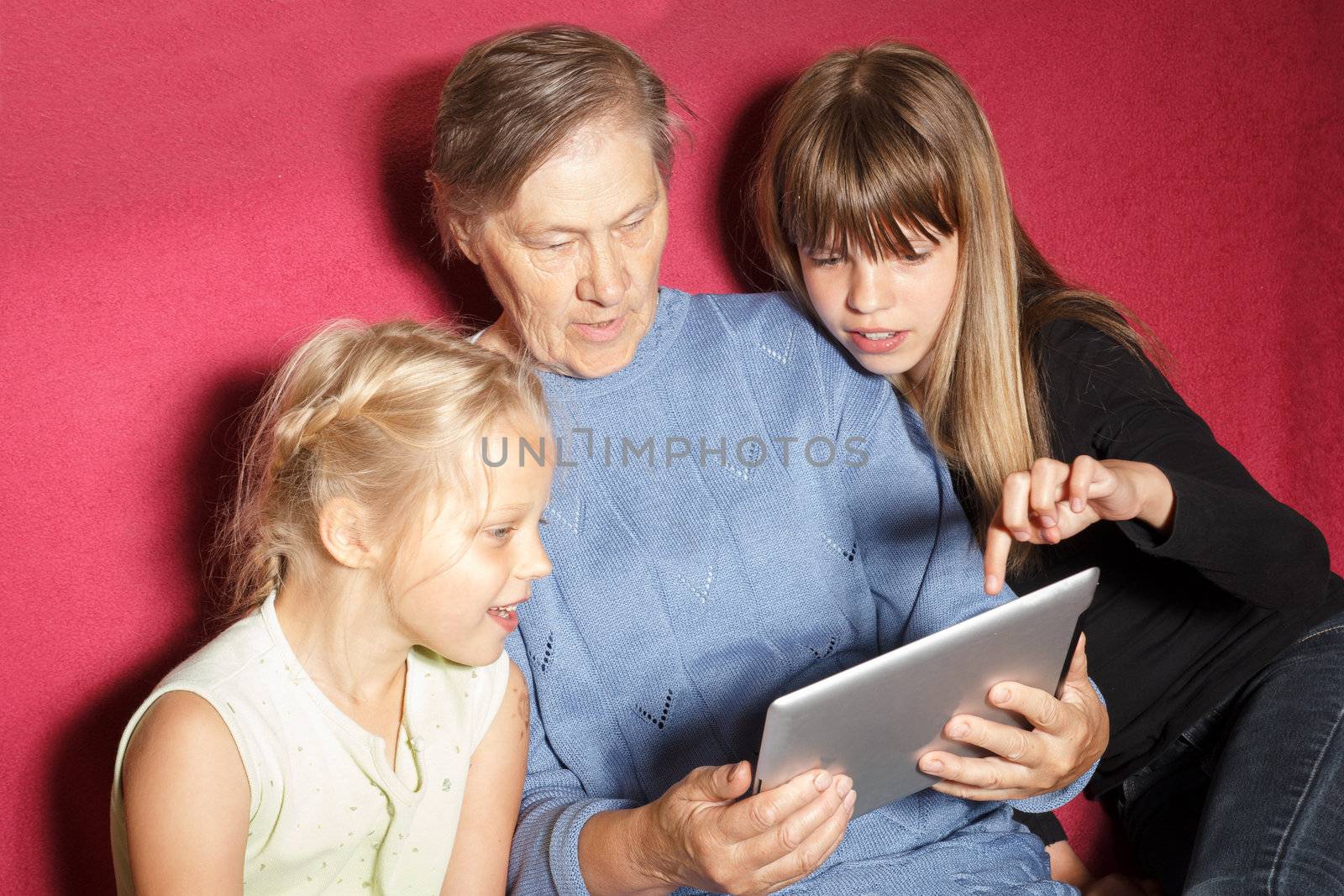 two sisters shows photos to his grandmother on the Tablet PC