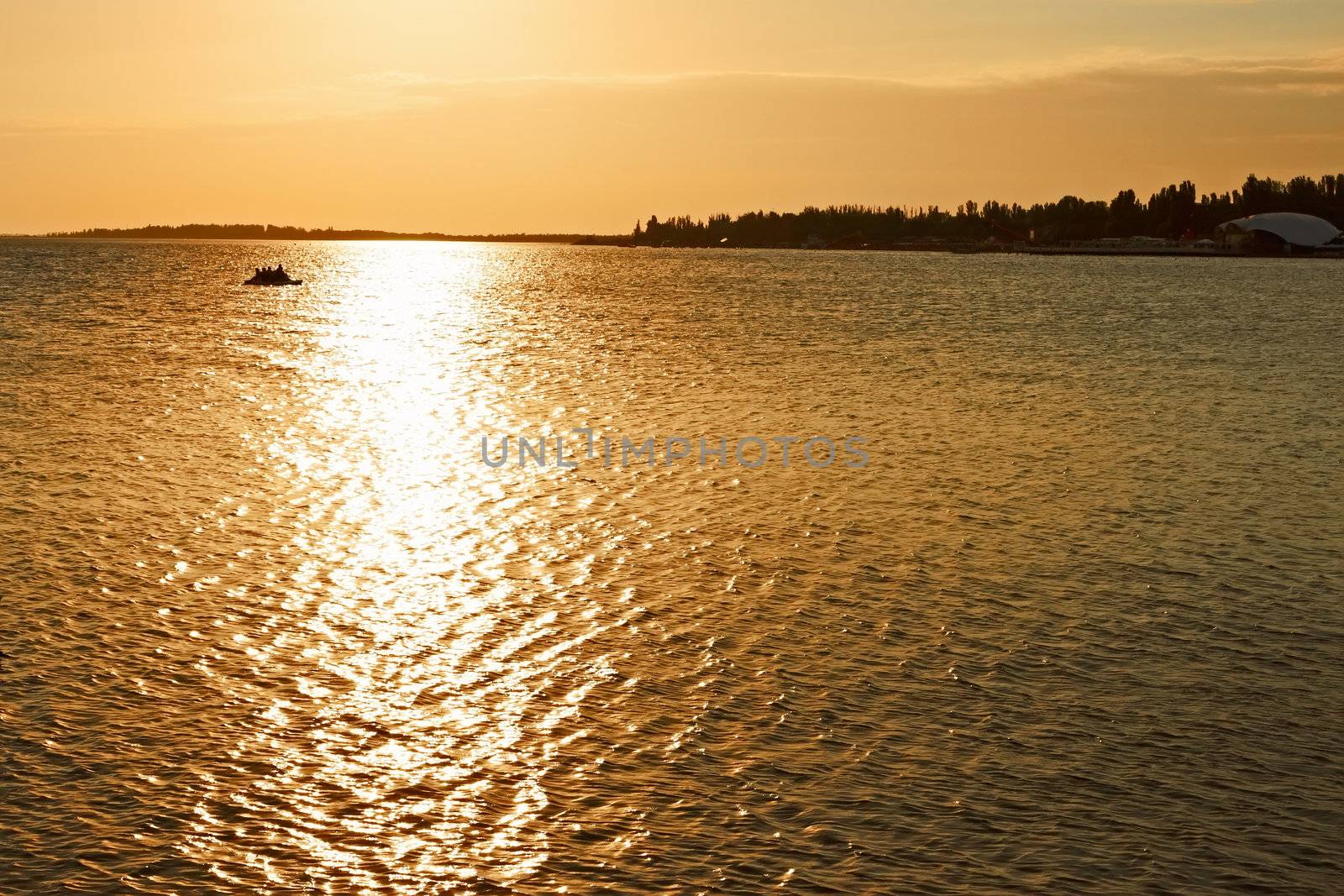 Remote beach coastline against the sea surface with setting sun reflection 