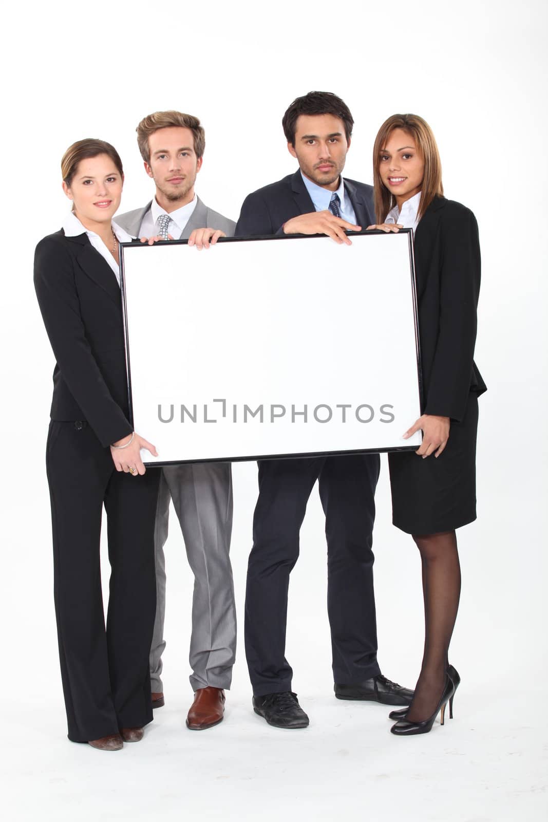 Four young executives holding a framed board left blank for your image by phovoir