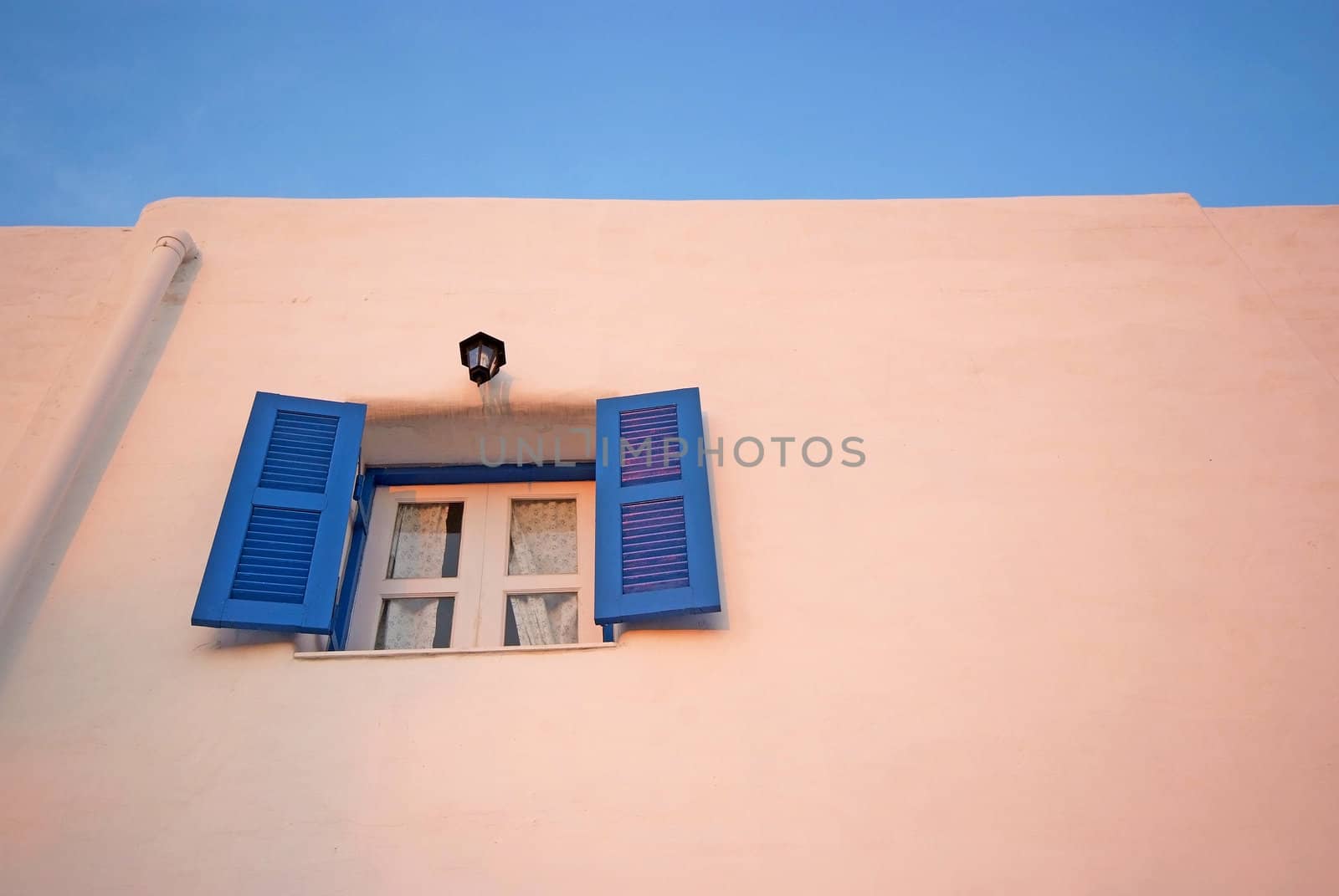 Vintage blue windows on the white wall and blue sky.