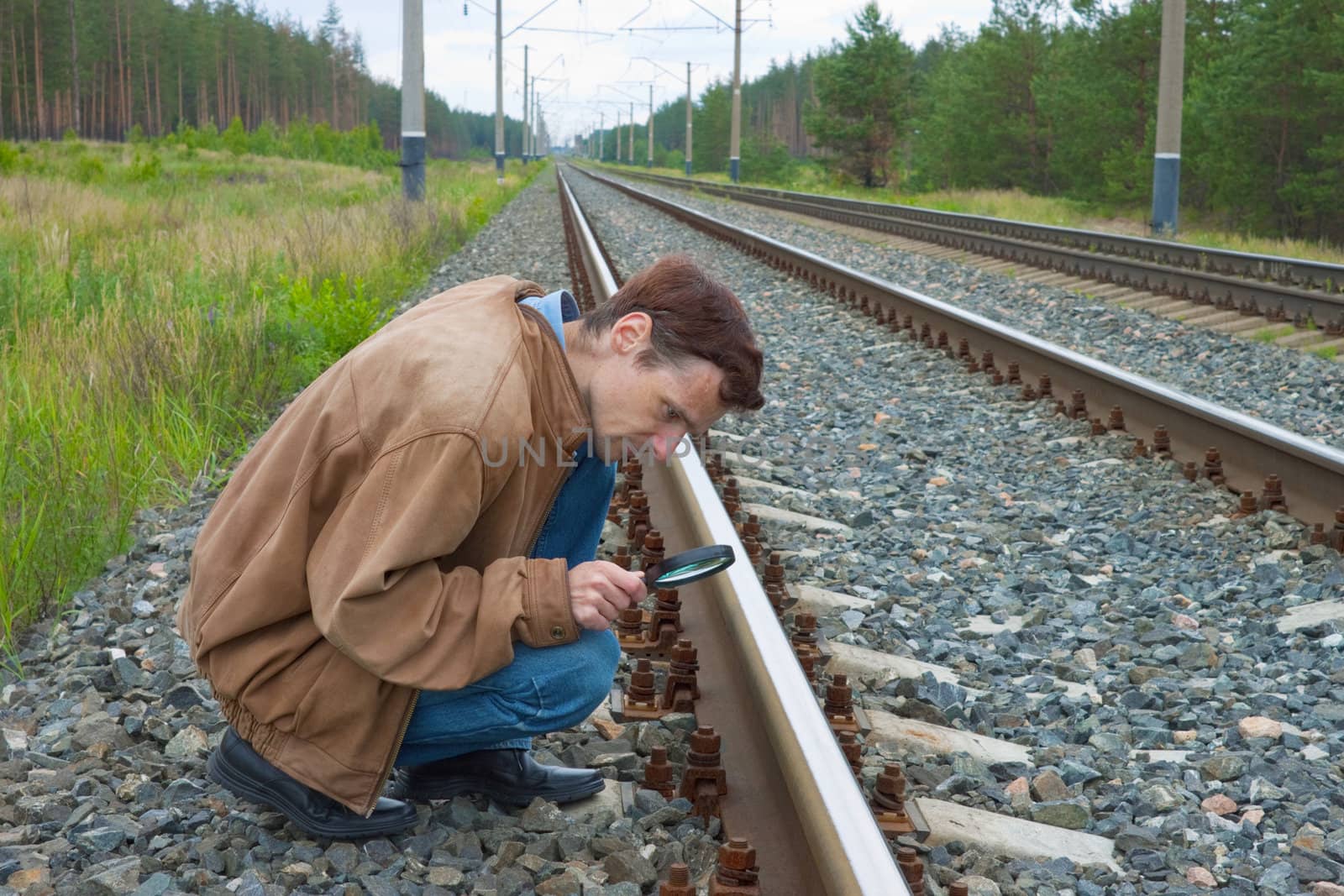 Man sits on railway and with enthusiasm examines something