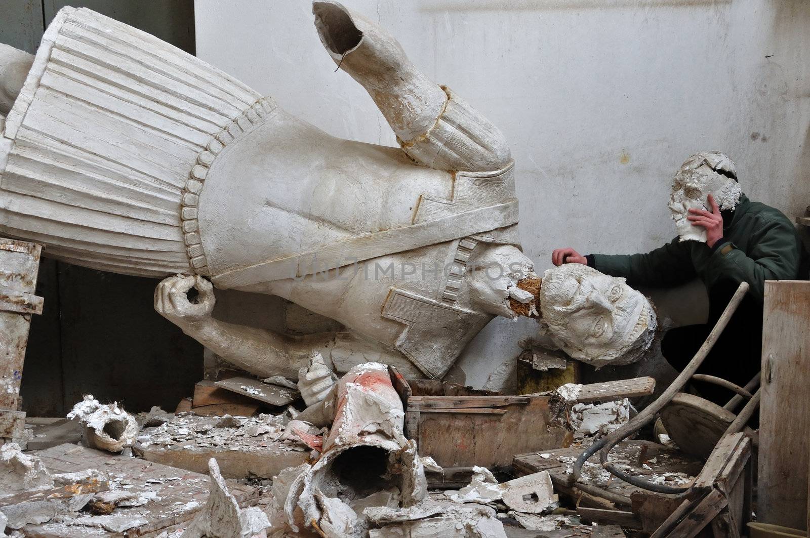Broken plaster statue of ancient god in the vandalized studio of Greek sculptor Nikolas Pavlopoulos (1909 - 1990). Abandoned interior and masked figure, Athens Greece, 2012.