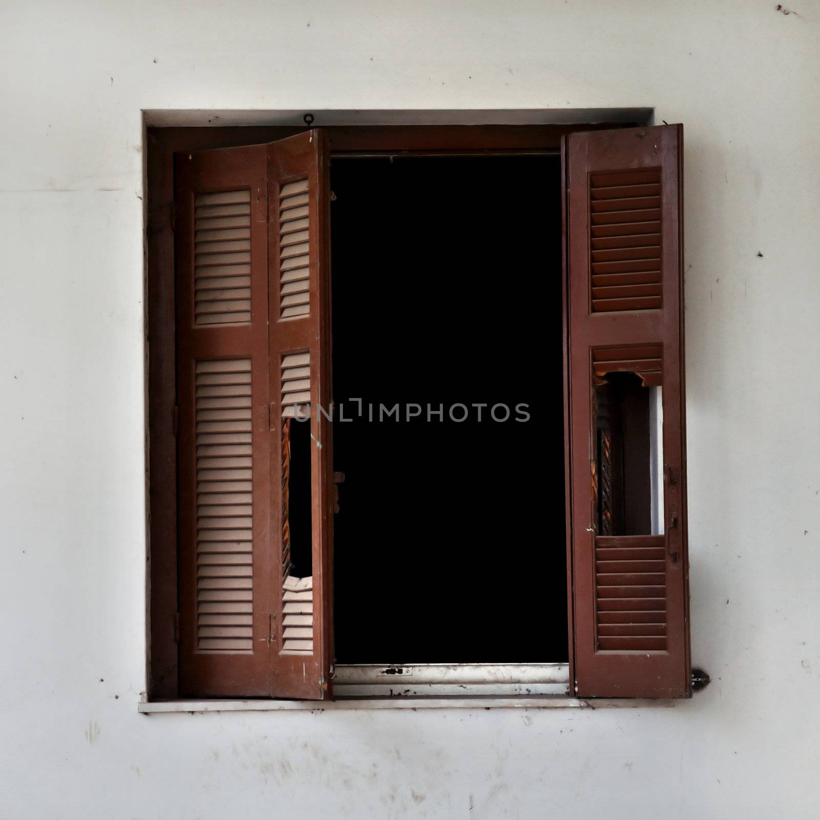 Wooden window shutter cracked open and dirty wall of an abandoned house.