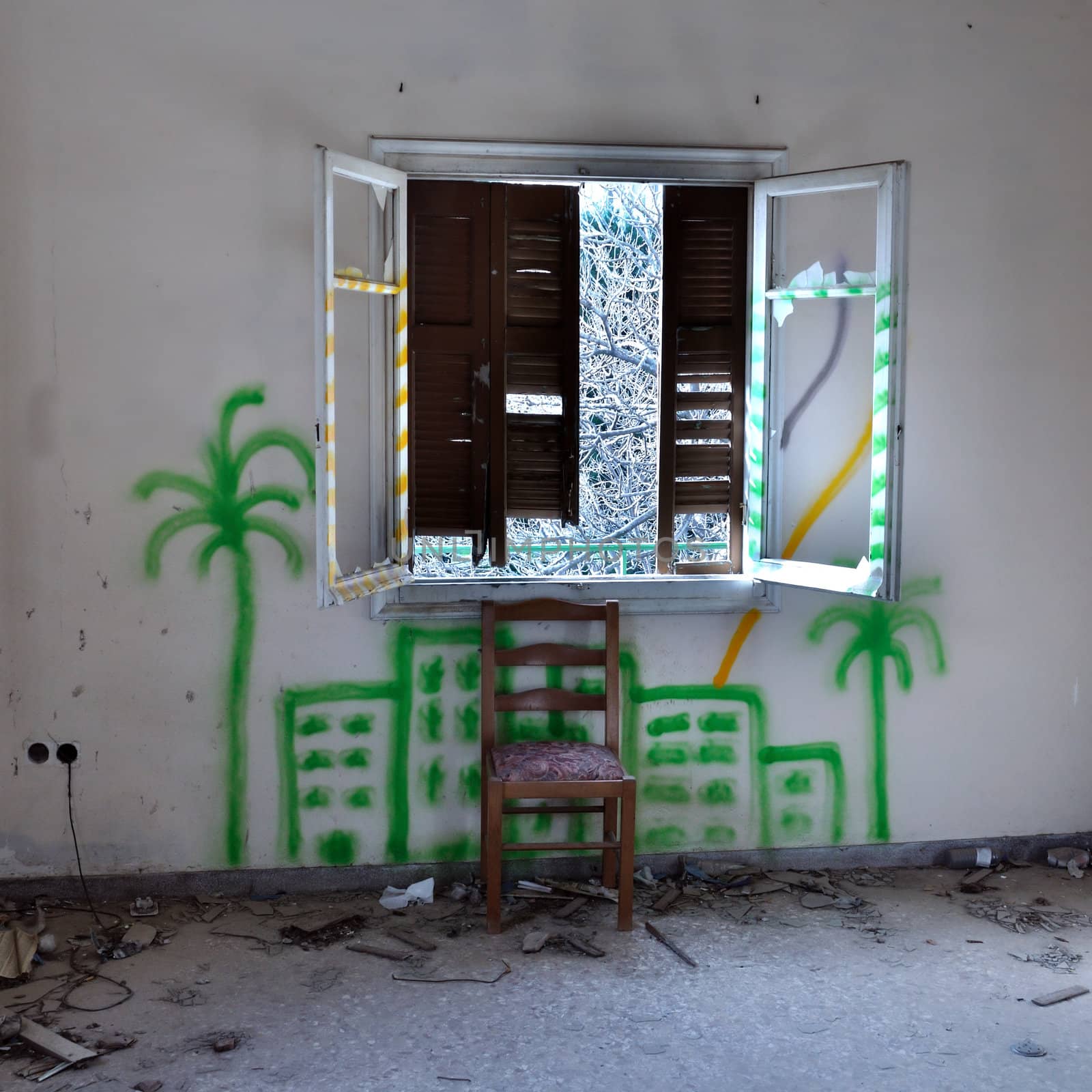 Chair and broken window in abandoned interior. City graffiti on the wall.