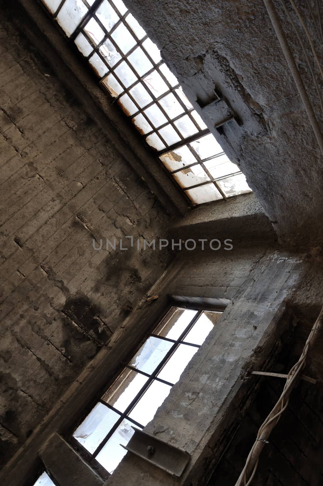 Broken windows concrete wall and ceiling in derelict factory. Industrial architecture.