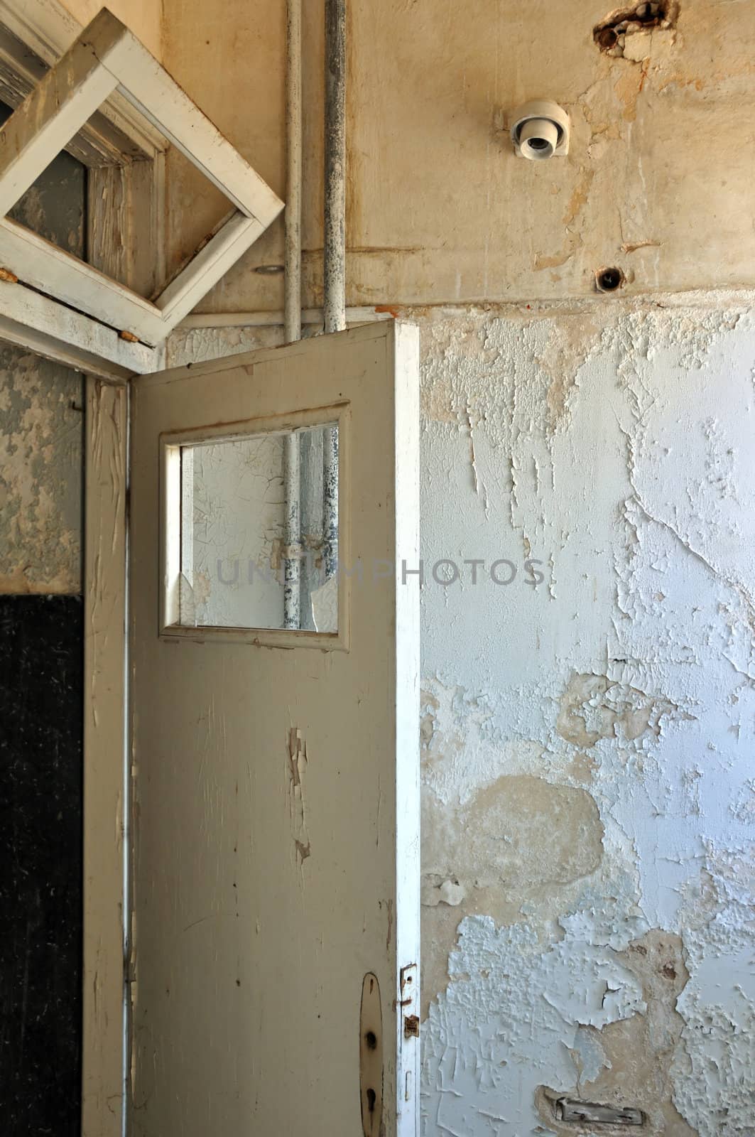 Door frame and peeling paint wall in abandoned house interior.
