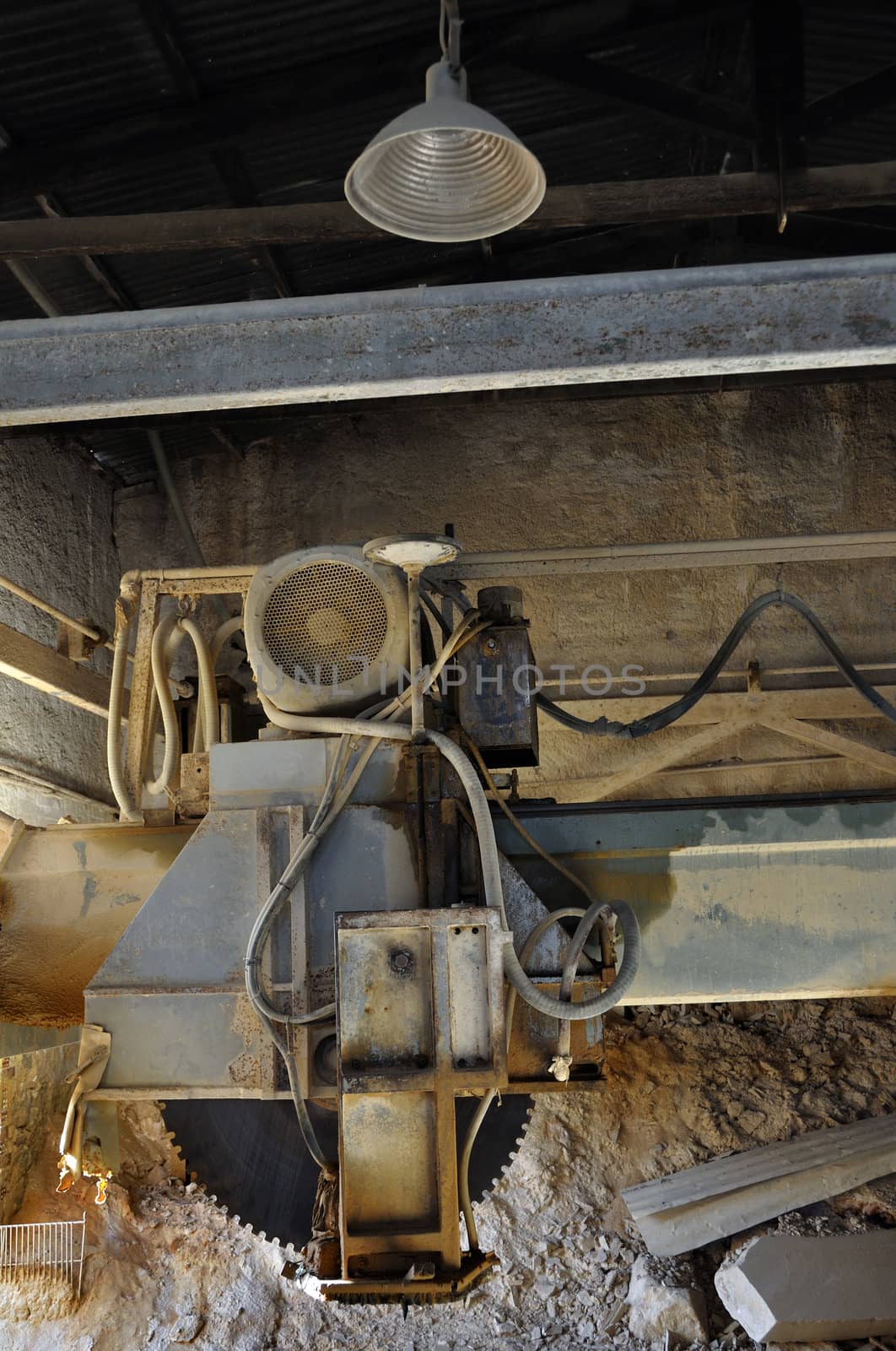 Dust covered cutting wheel in abandoned marble processing factory interior.