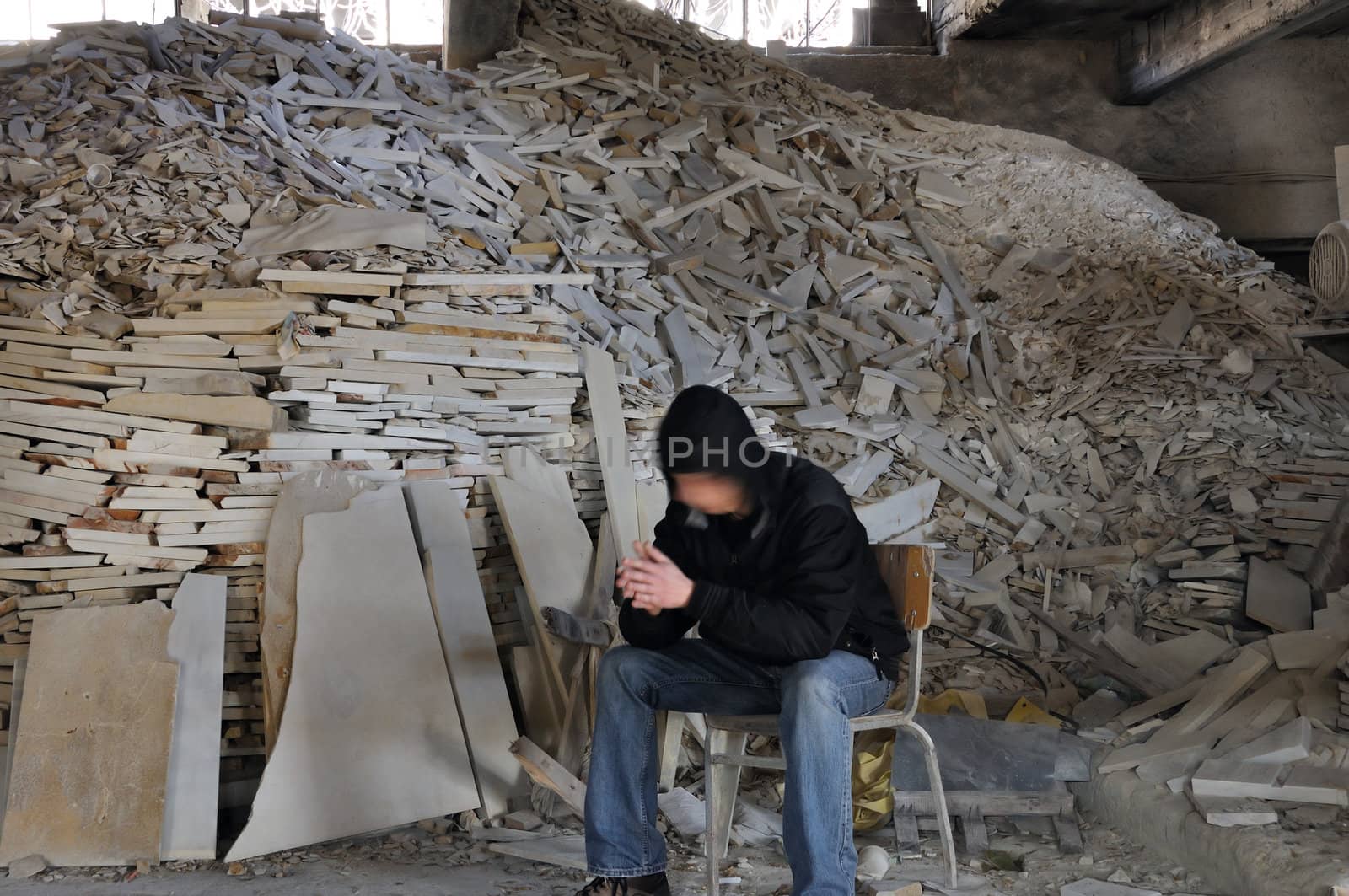 Man sitting next to pile of broken marble in abandoned interior. Motion blur.