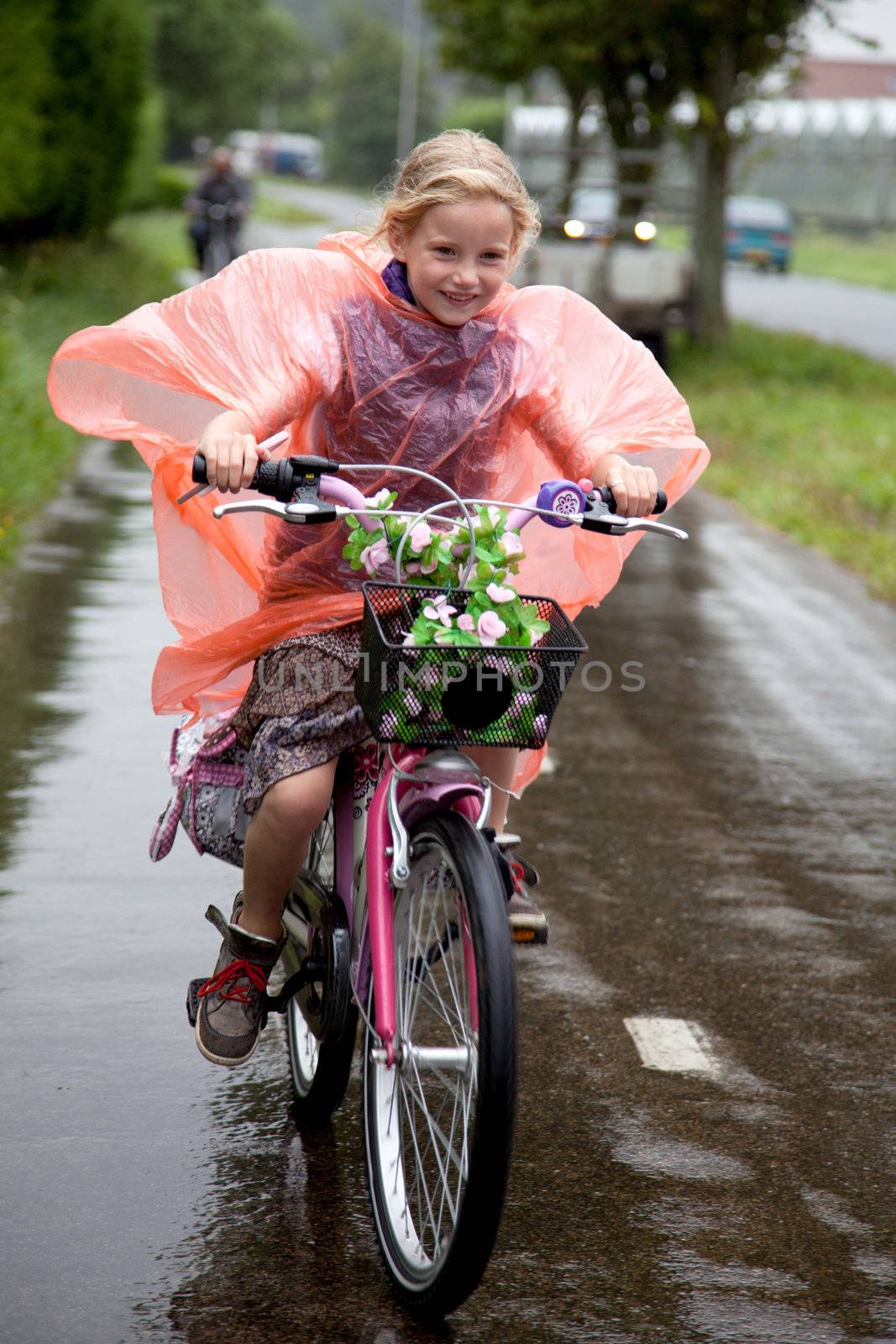 girl with plastic poncho cycling in the rain