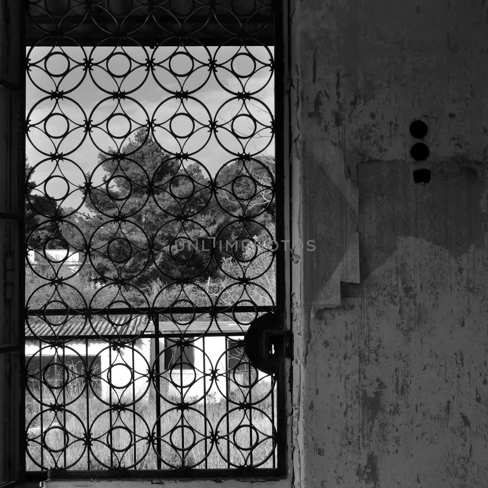Vintage metal door with circles pattern and peeling wall of an abandoned house.
