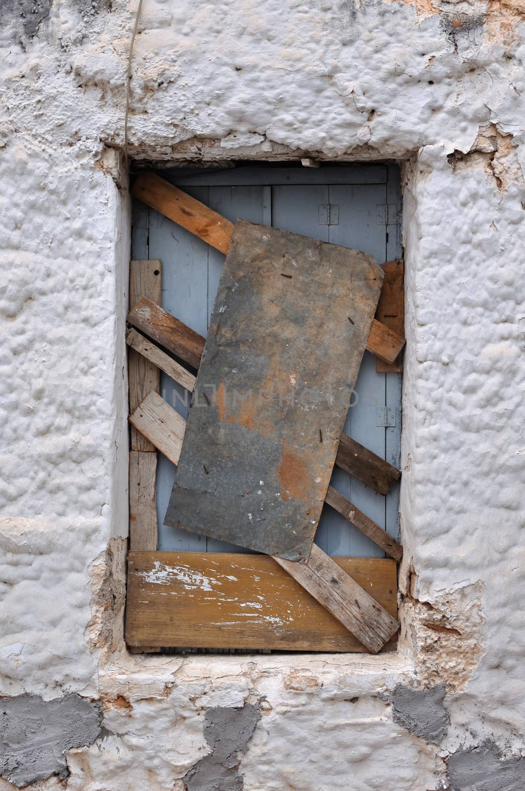 Boarded up window frame of an old house and rough wall background texture.