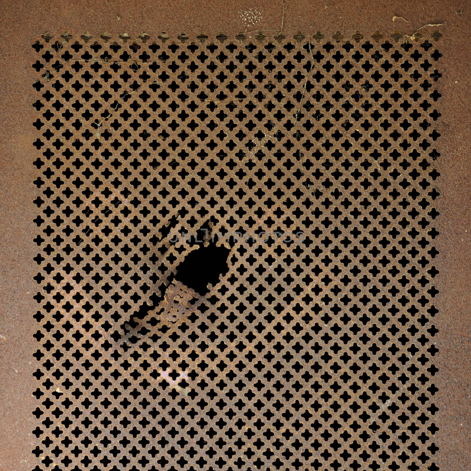 Rusty perforated metal surface. Worn iron grille background texture.
