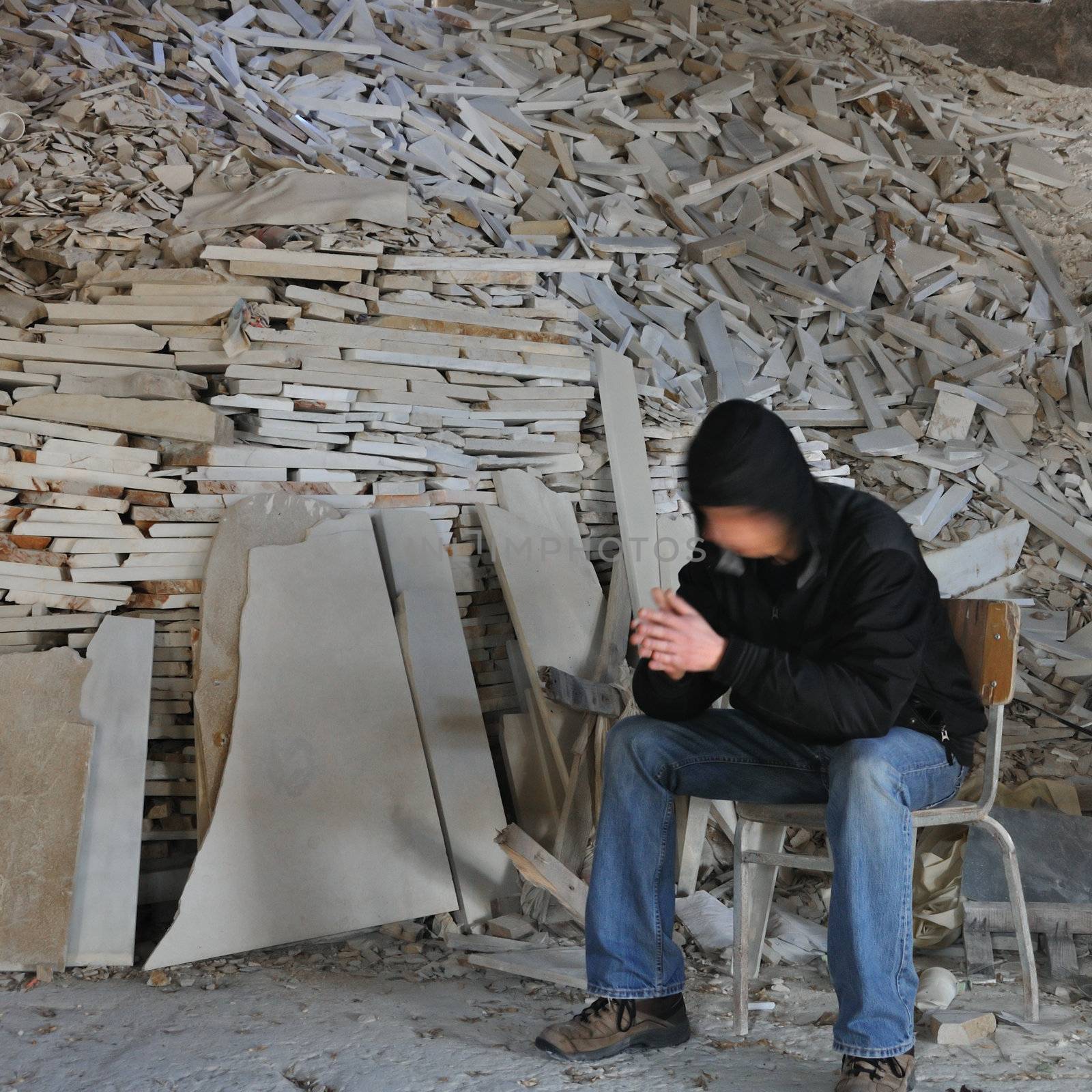 Motion blurred man sitting next to a pile of marble fragments in abandoned interior.