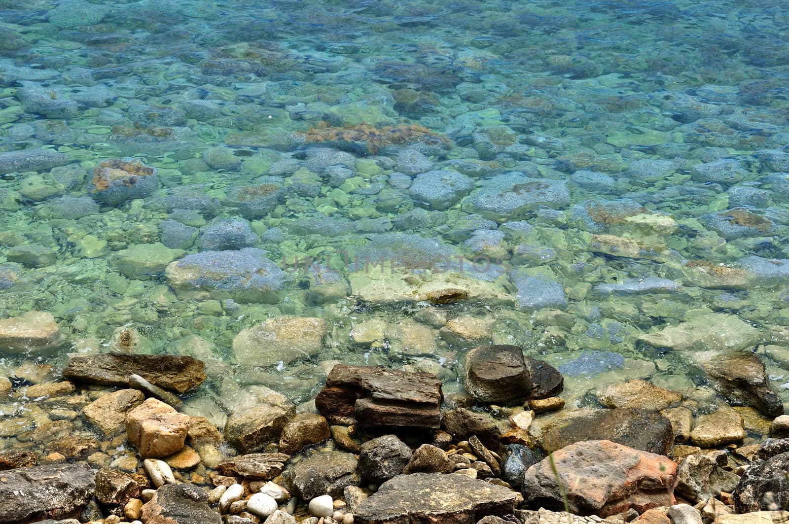 Clear blue sea water and stone beach background.
