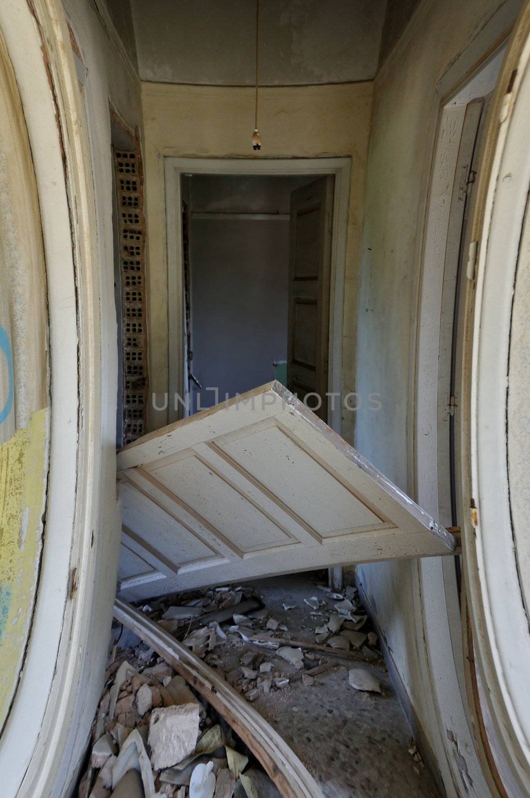 Unhinged door and debris in the corridor of an abandoned house.