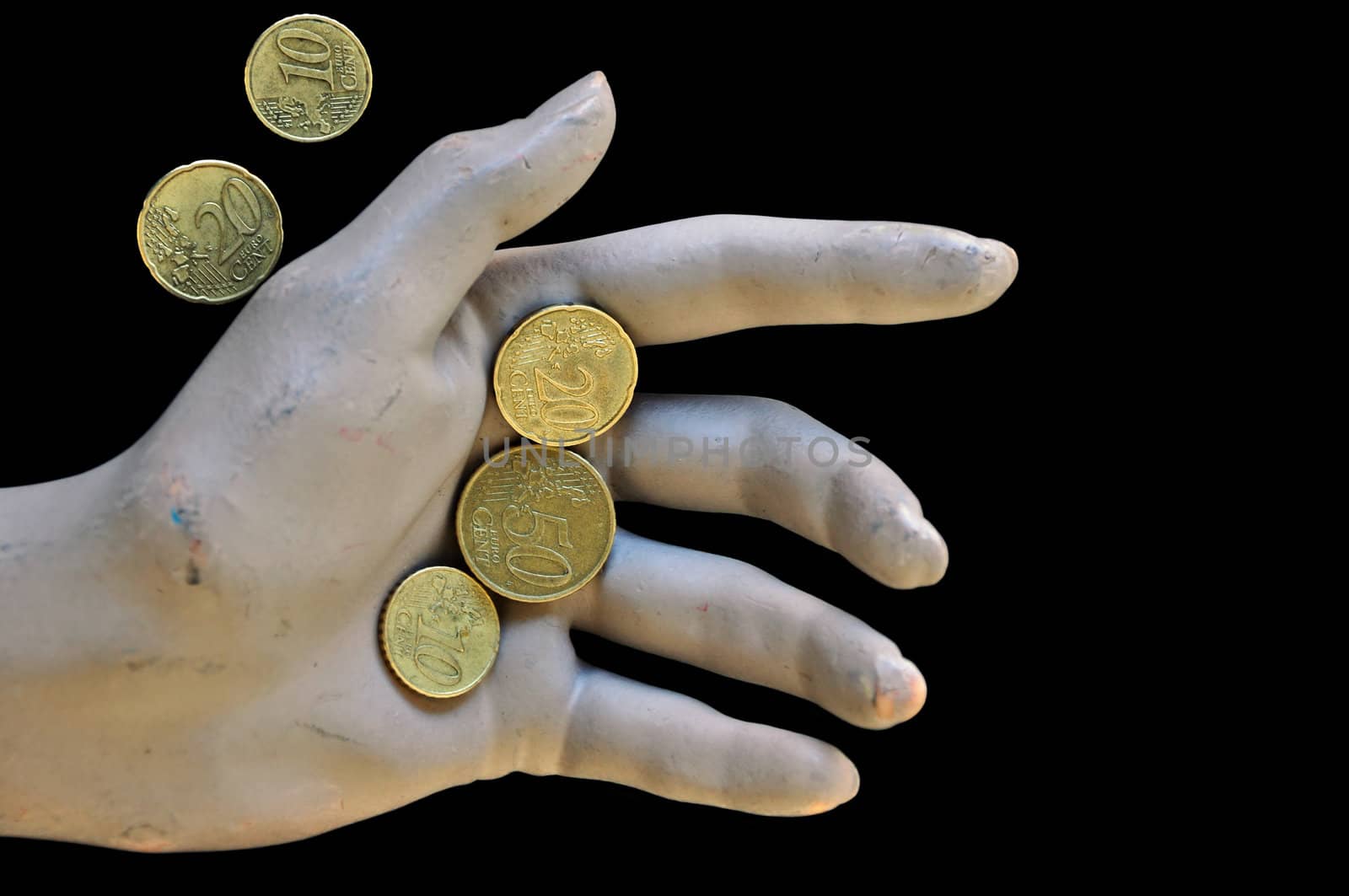 Worn doll hand holding euro coins. Economic and financial issues.