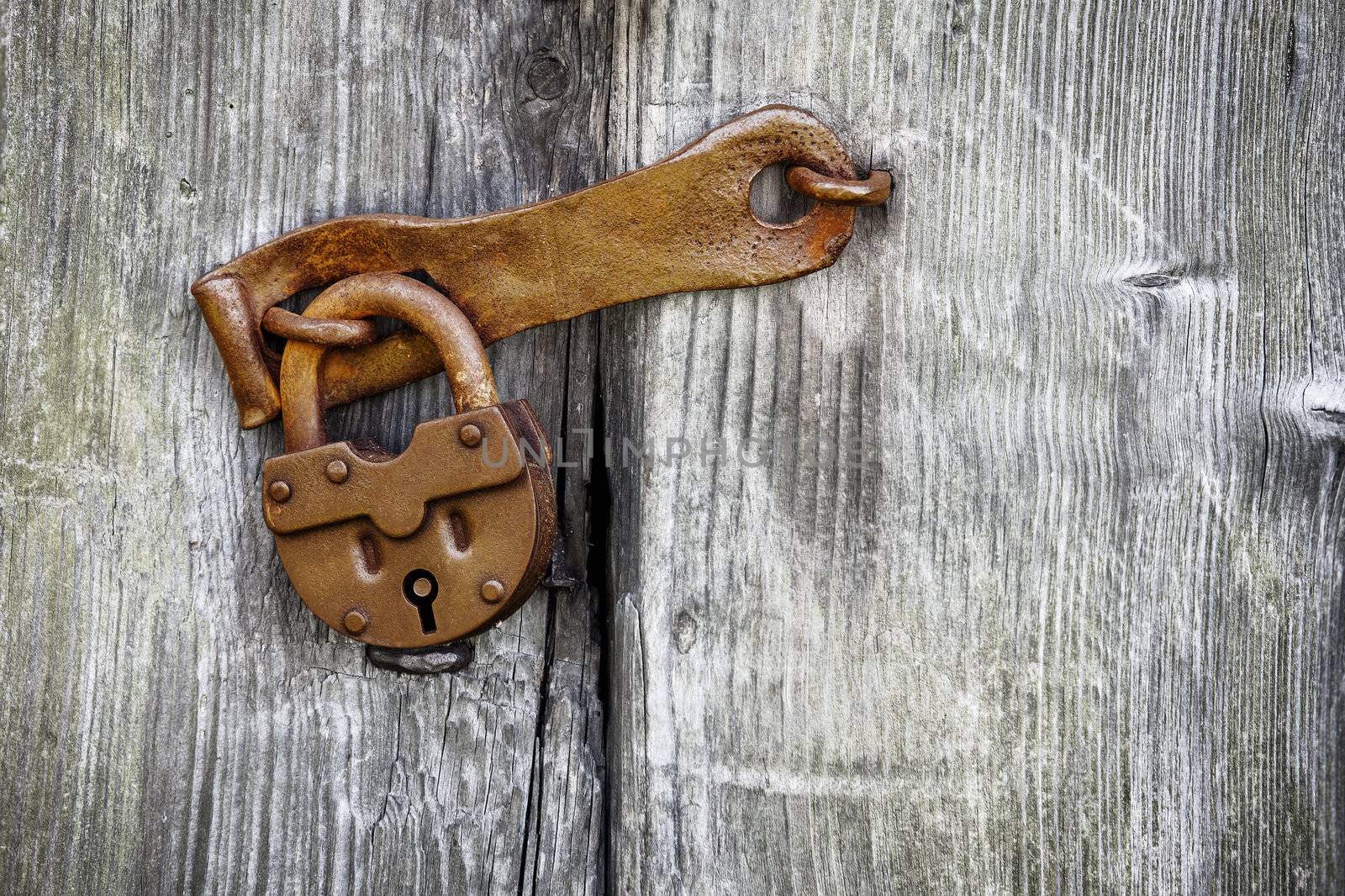 Old rusty padlock on a wooden door