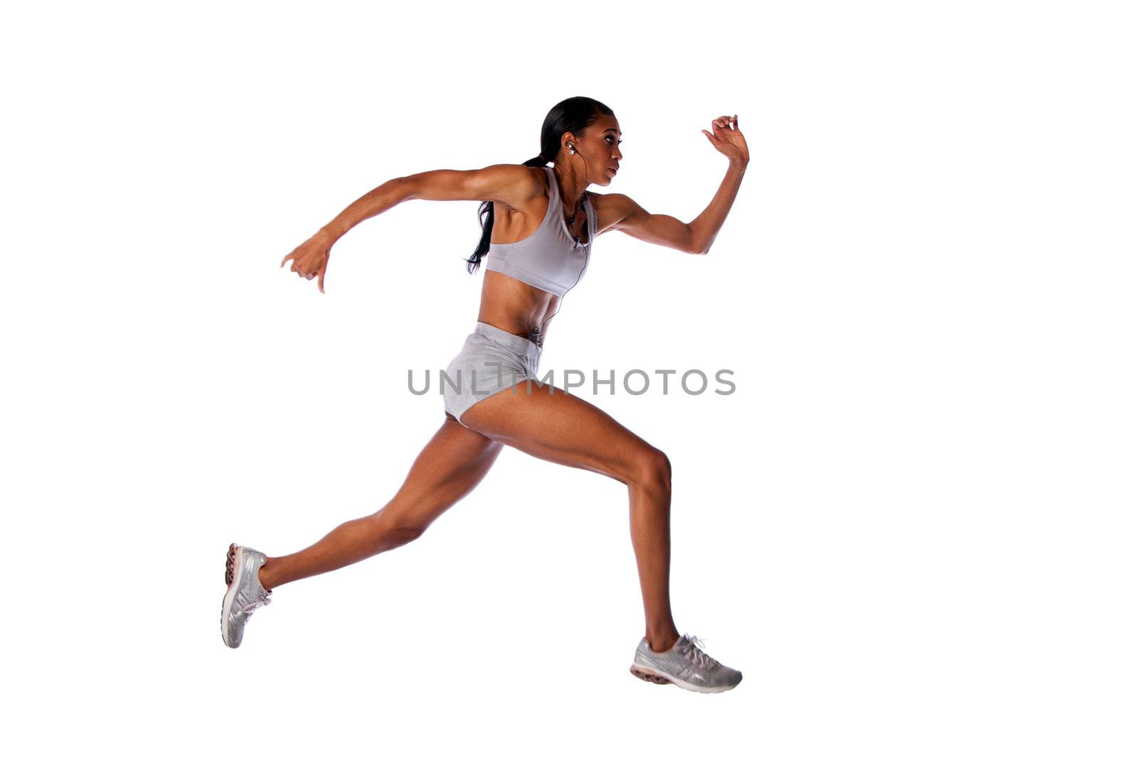 Beautiful fast running female athlete with toned muscular fitness body in grey with headset listening to music while exercising, isolated.