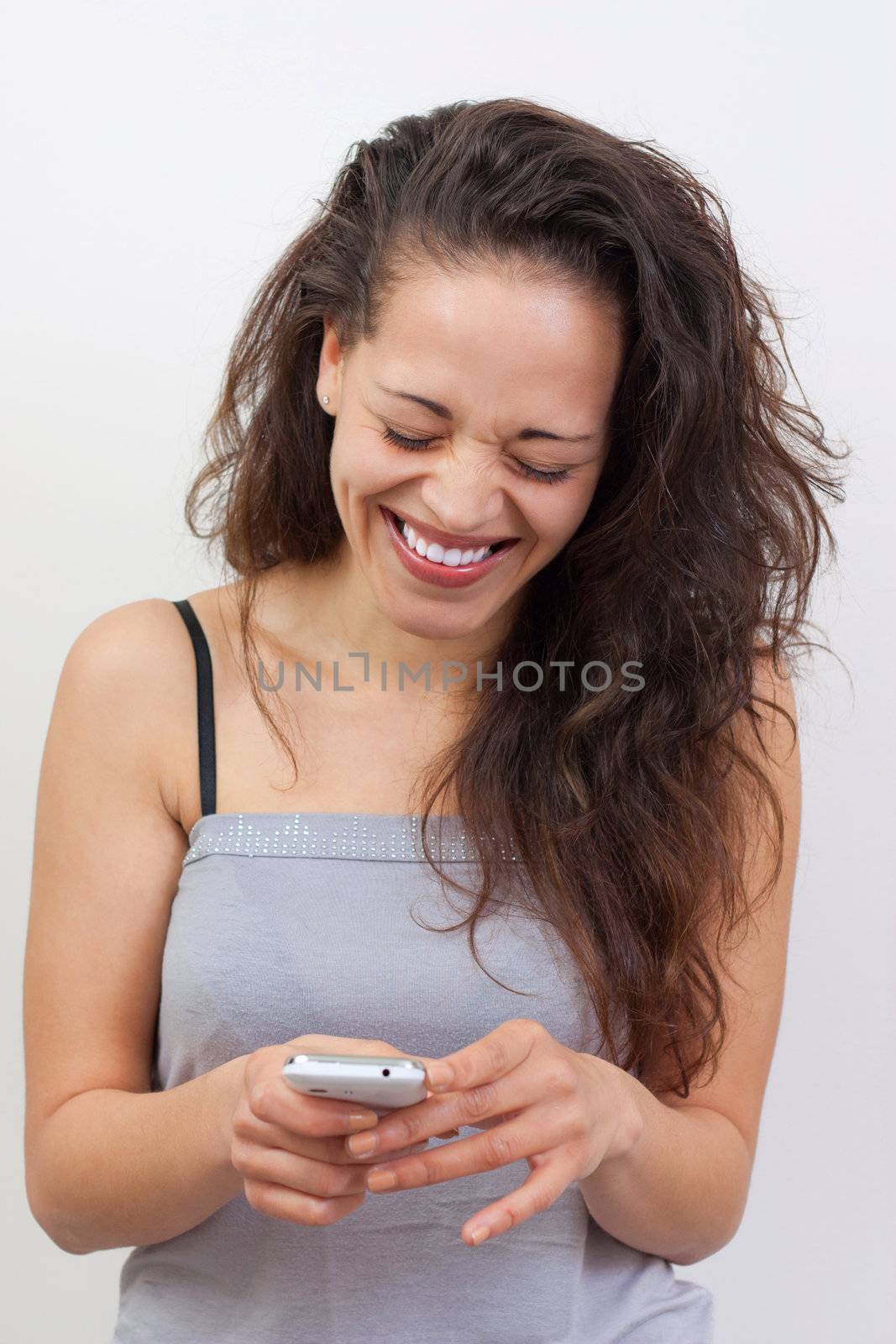 Happy young woman writing a message on her smartphone with a a big smile