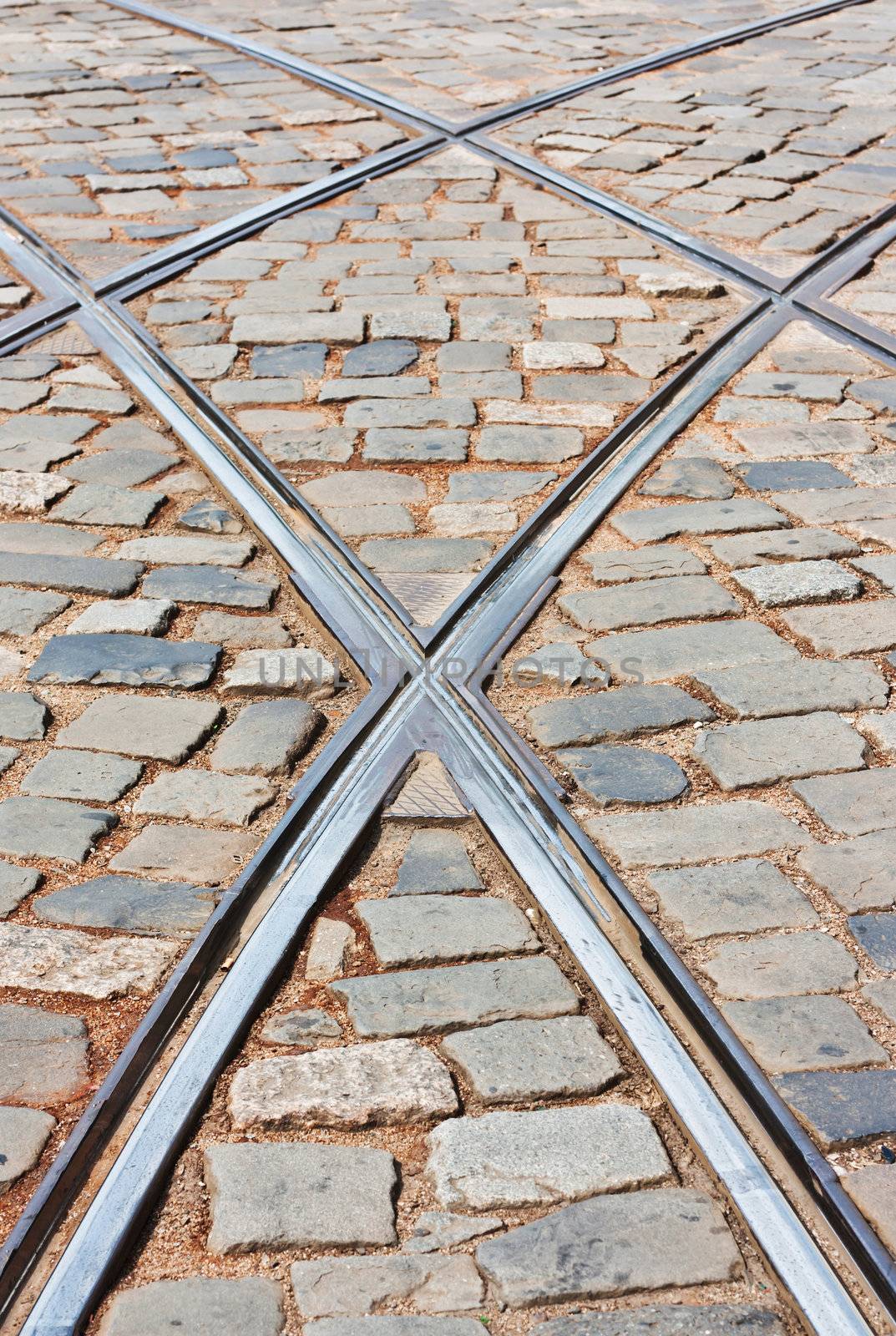 Rails of tramway crossing street car on a paved street