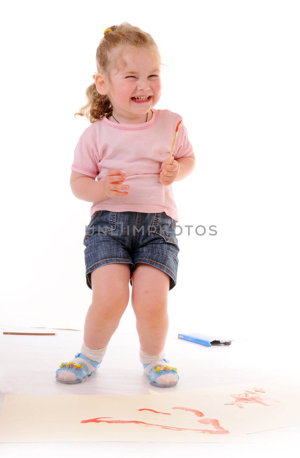 Laughing small blonde girl with paintbrush