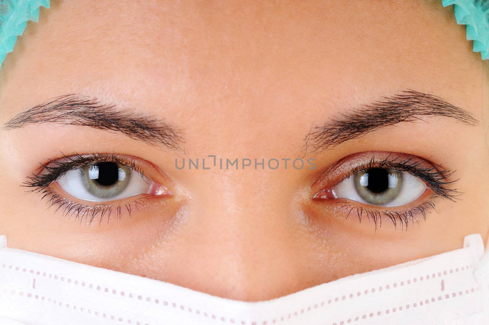 Close-up of a woman doctor's eye wearing a mask examining you.