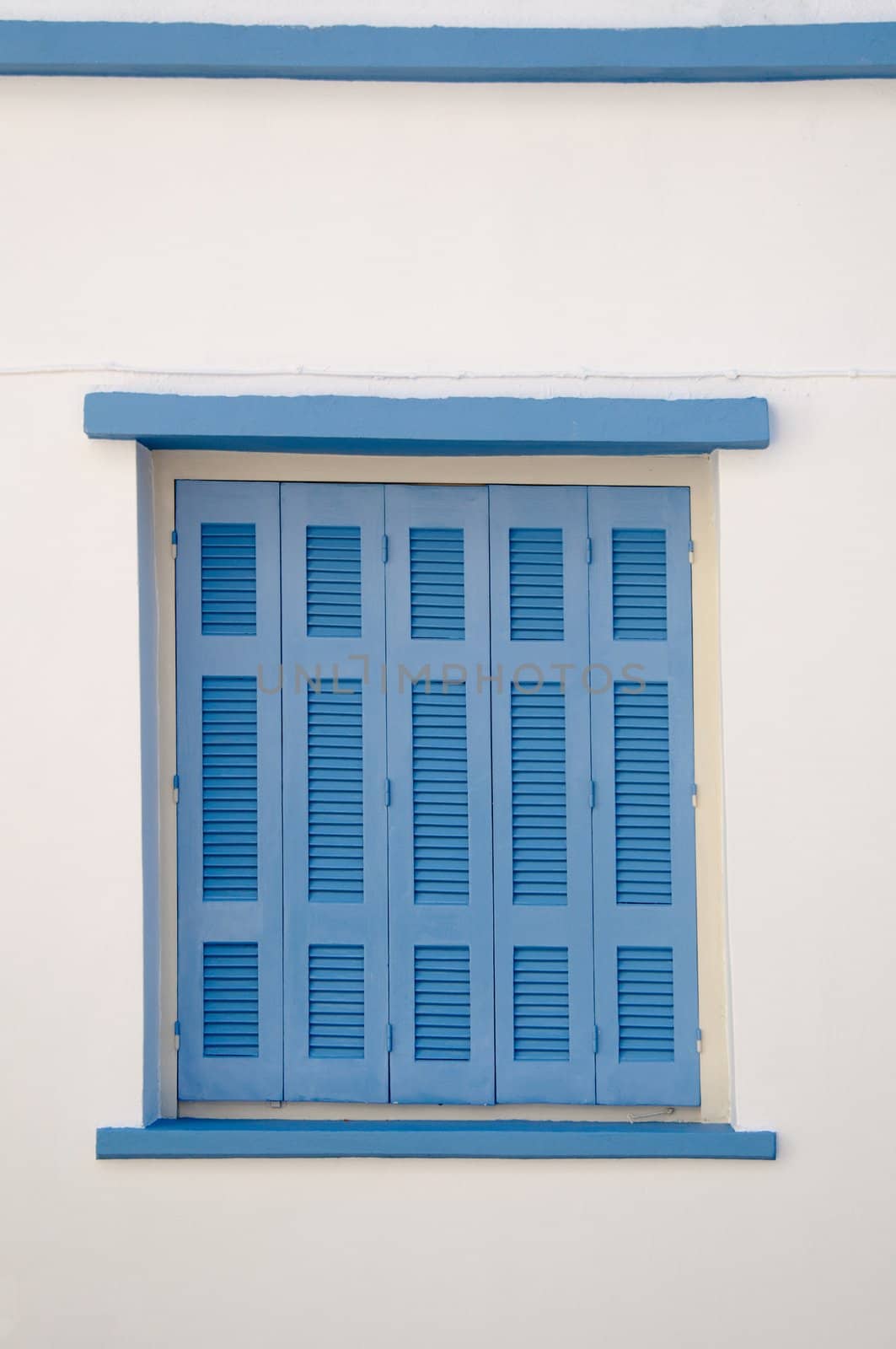 Greek style house in blue and white with wooden blue window shutters