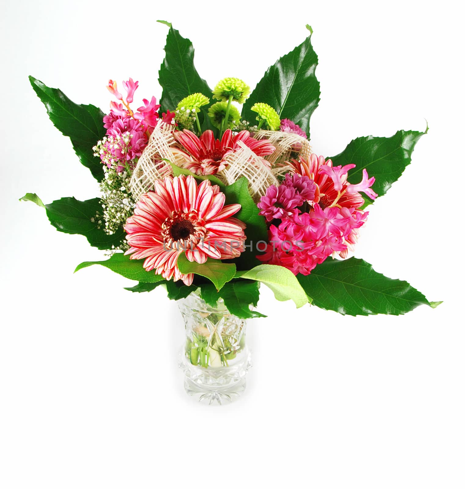 Beautiful bouquet of fresh vibrant gerbera flowers arranged in a green leaf and glass vase - isolated