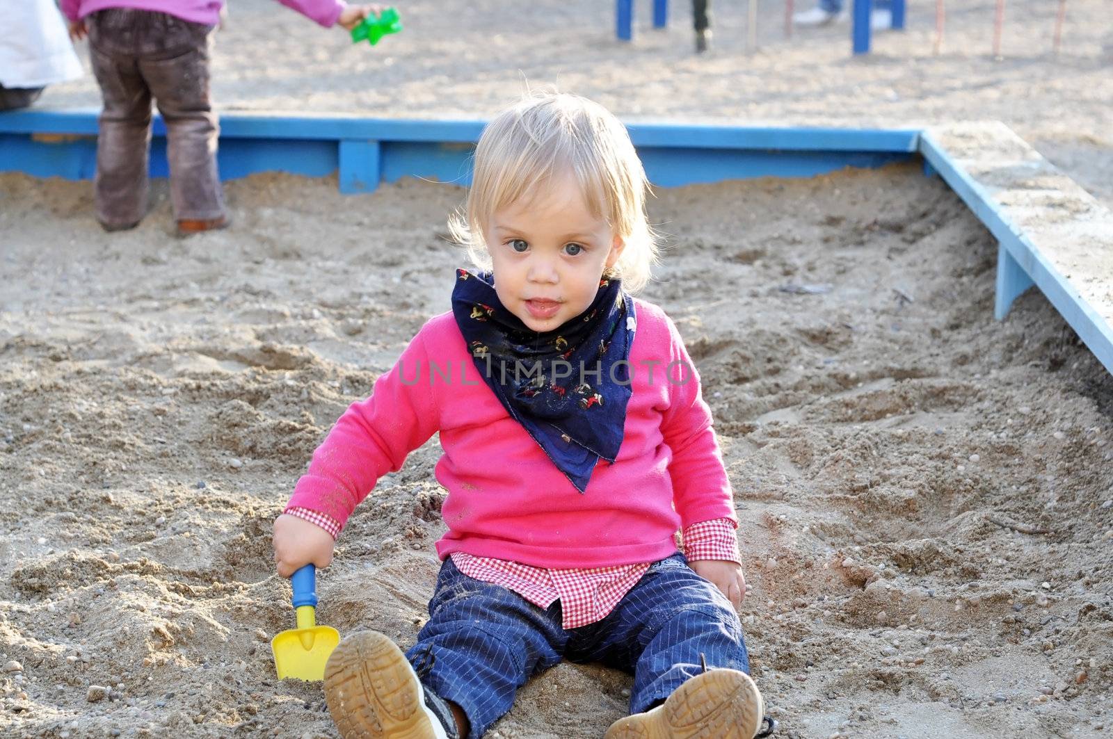 two years old blonde blue eyes beautiful kid at the playground