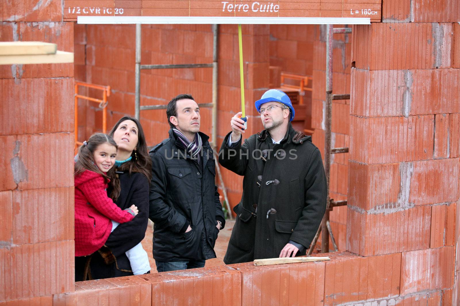 family and contractor on construction site by phovoir